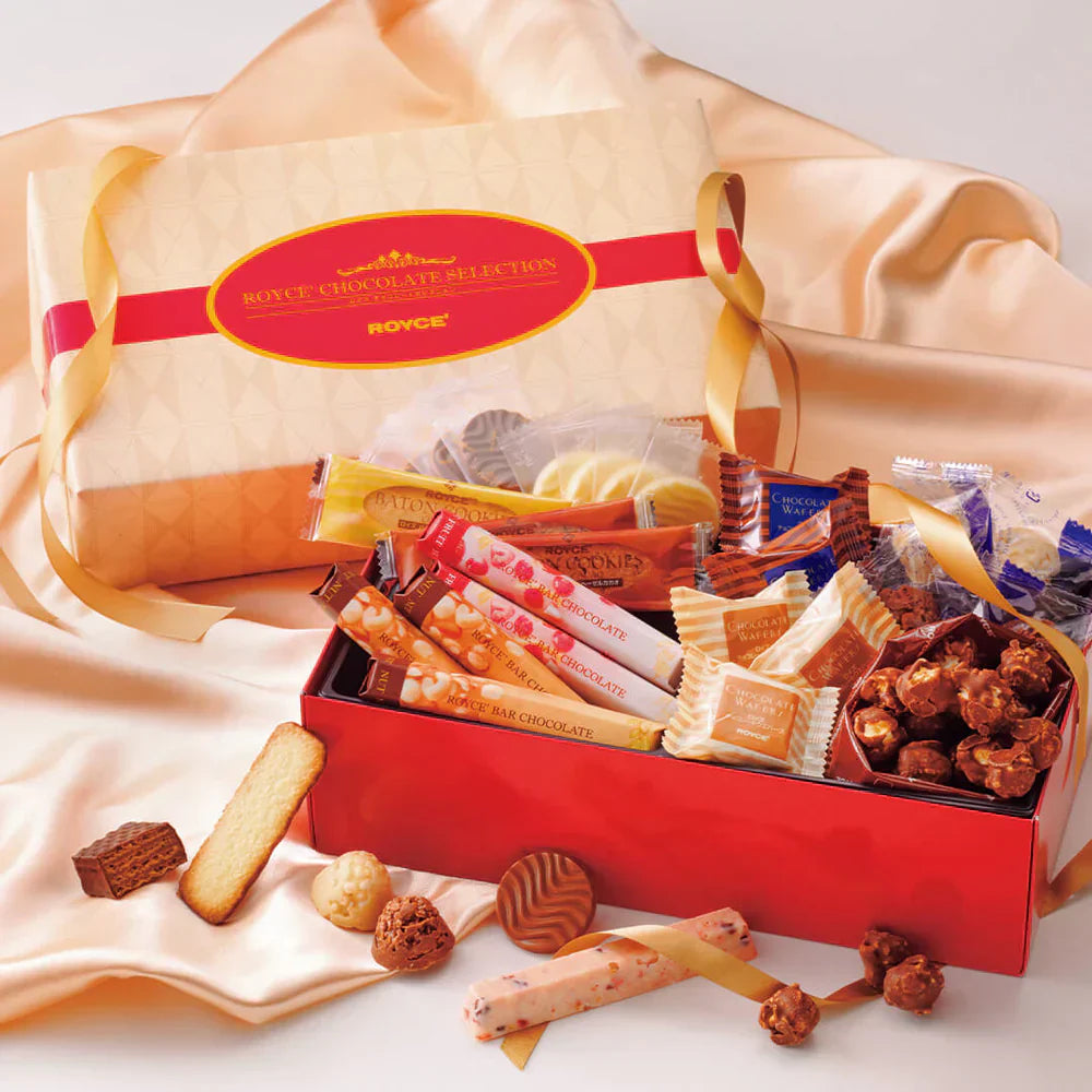 Red tin with gold ribbon filled with assorted Royce chocolates: rolled sticks, wafers, cookie bars, truffles, and chocolate-coated popcorn.