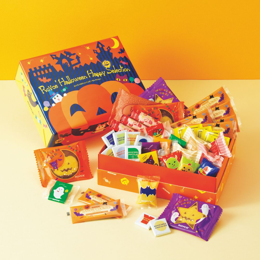 Halloween-themed gift box from Royce, featuring orange packaging with pumpkins and bats, containing assorted chocolates and cookies in festive Halloween wrappers.