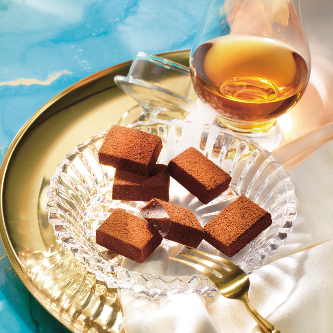 ROYCE' Chocolate - Image shows chocolate blocks on a plate with a gold tray and a glass with rum.
