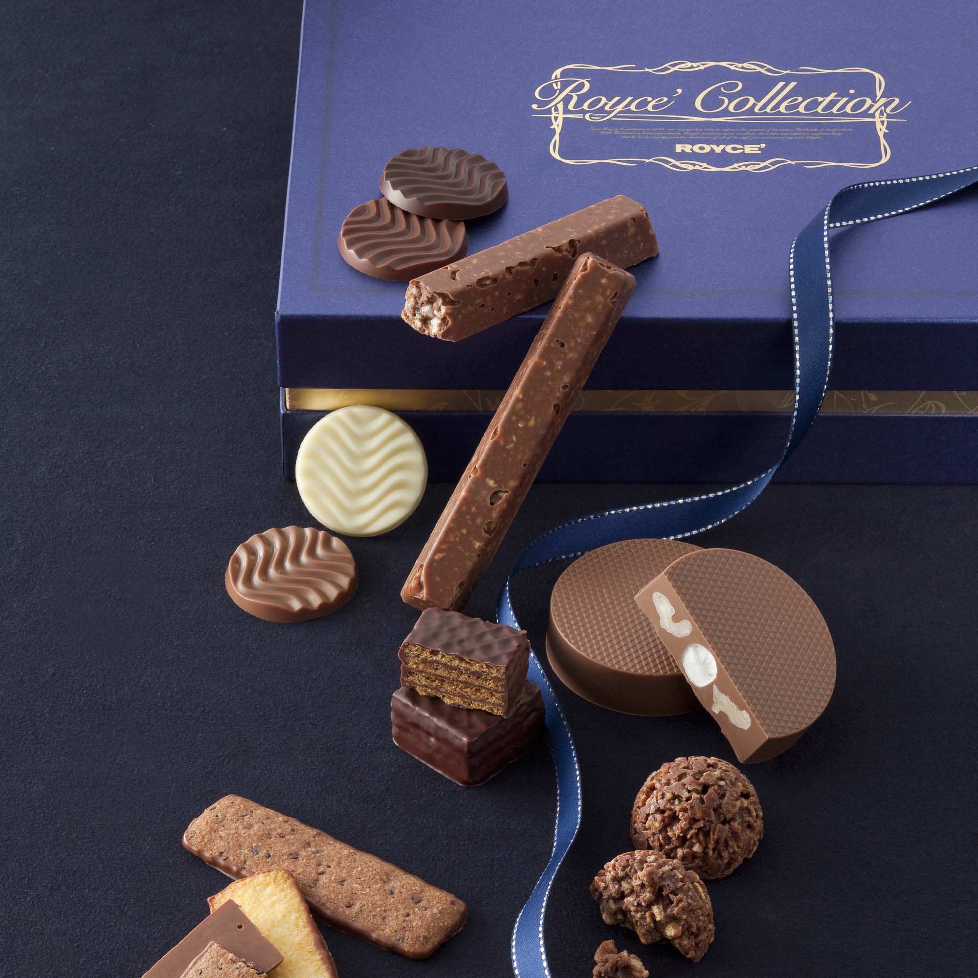 Assorted Royce' chocolates, including discs, bars, wafer bites, cookie-style bars, and truffle-style clusters, elegantly arranged in a blue gift box with ribbon.