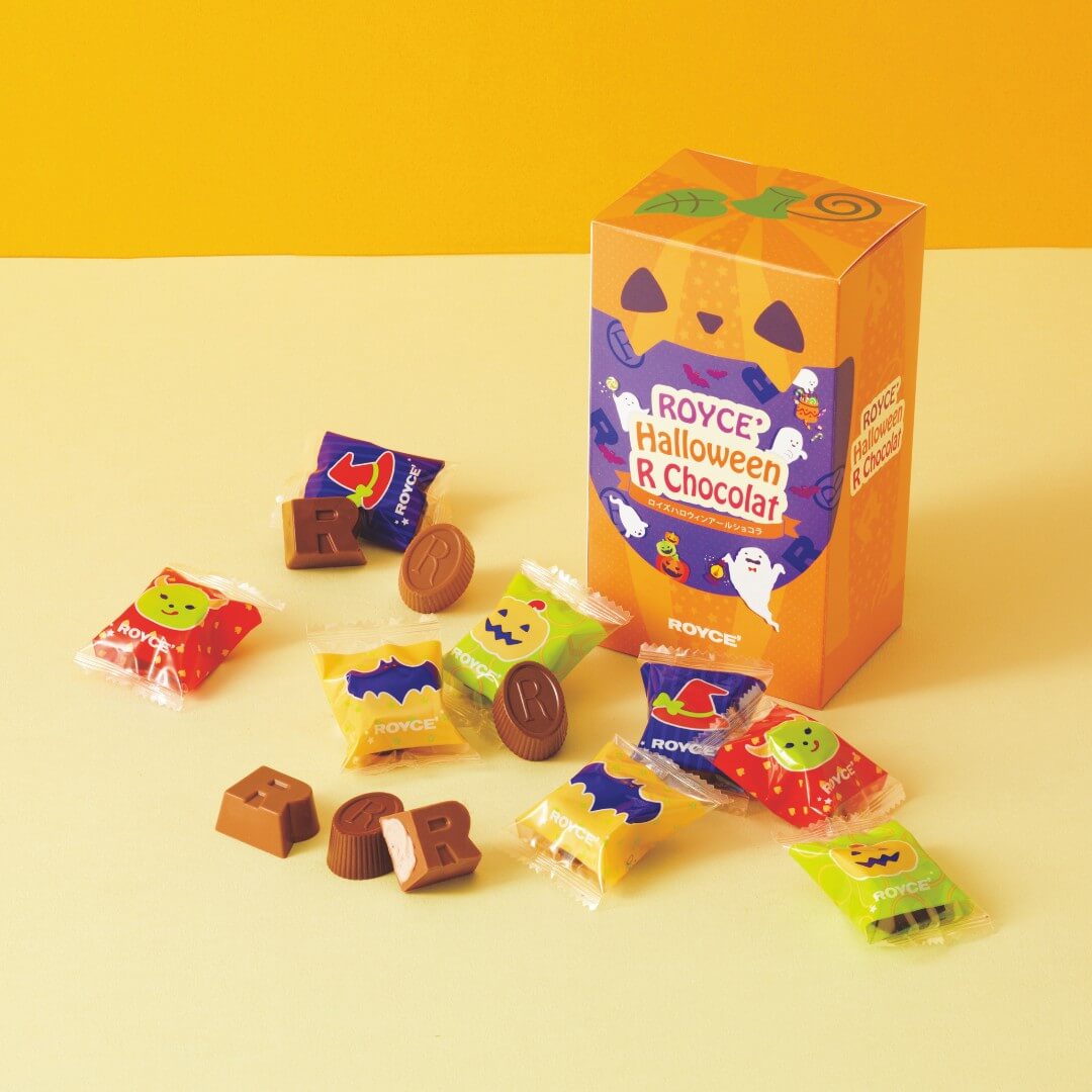 Festive Halloween-themed Royce “R” Chocolat box, jack-o’-lantern design, with assorted colorful wrapped chocolates featuring Halloween motifs like pumpkins, bats, and ghosts.