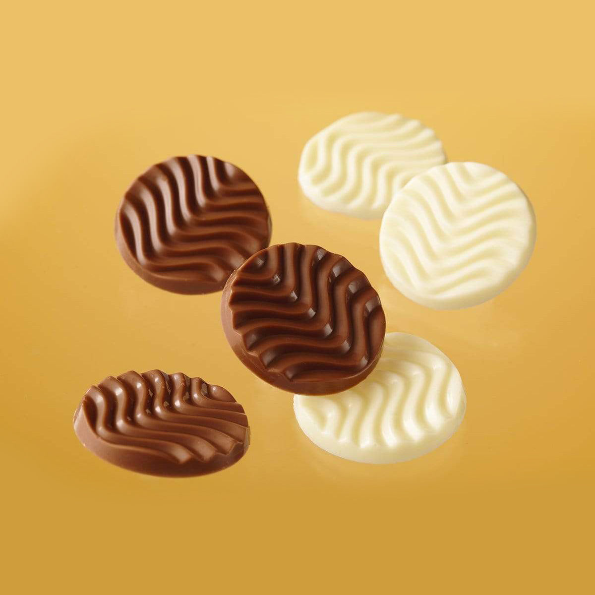 Six round Pure chocolate wafers, three milk and three white, feature a wavy ripple pattern on top, floating against a plain background.