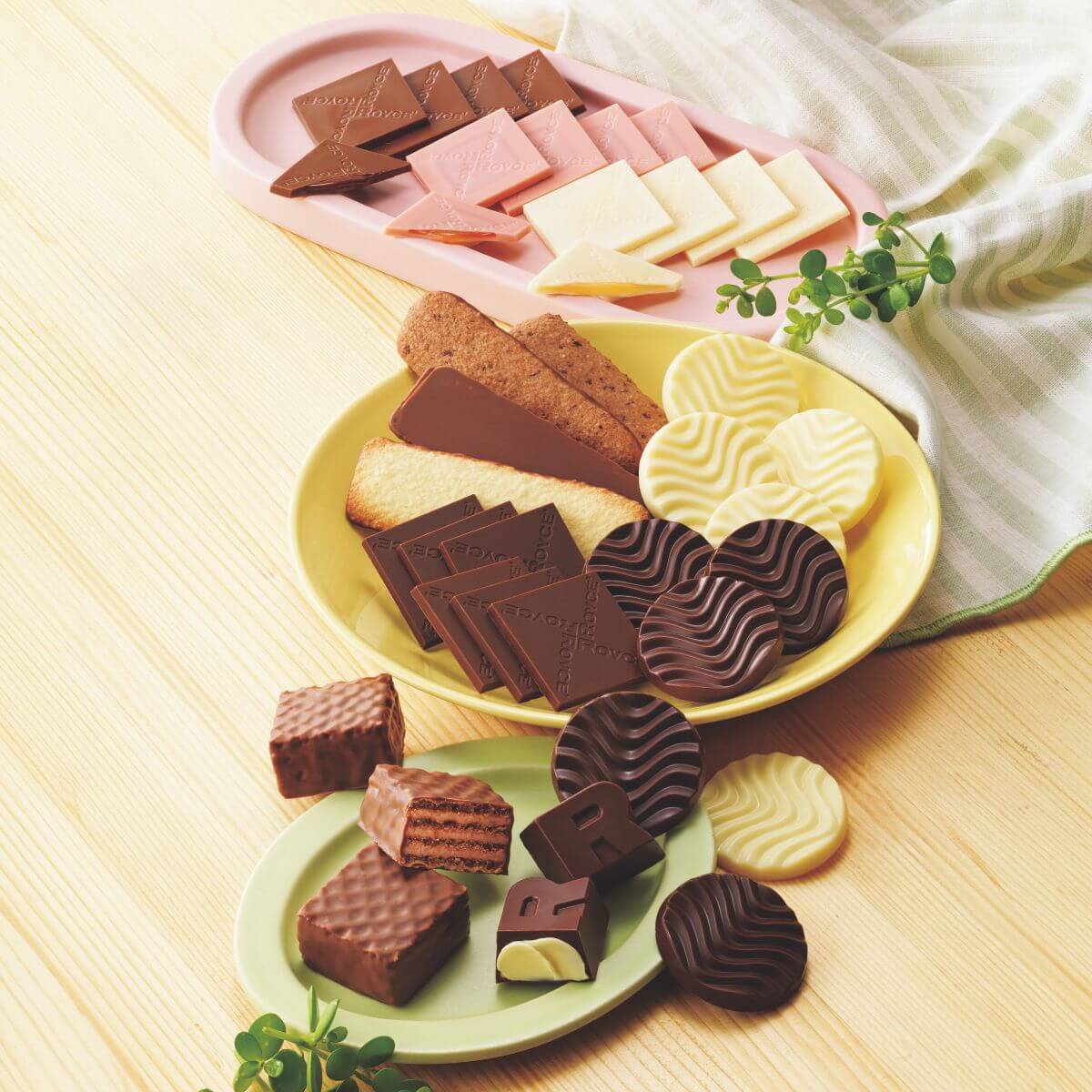 Chocolat No Shiki Hokkaido features plates filled with assorted chocolates and chocolate-dipped cookies and wafers, showcasing diverse shapes and flavors for a delightful tasting experience.