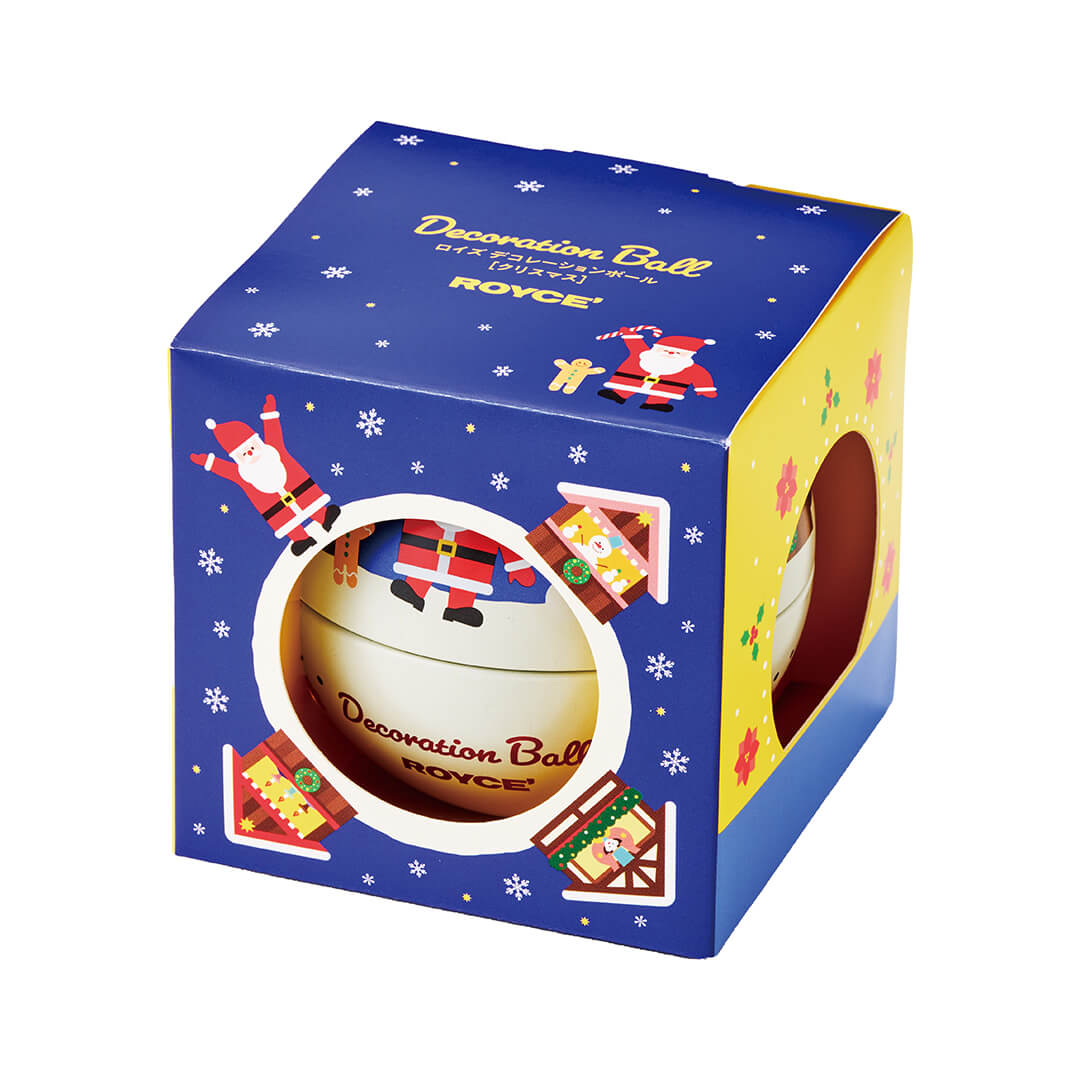 ROYCE' Chocolate - Decoration Ball "Christmas" - Image shows a printed blue and yellow box with illustrations of snowflakes, houses, flowers, wreaths, and Santa Claus. Text says Decoration Ball ROYCE'. Background is in white.