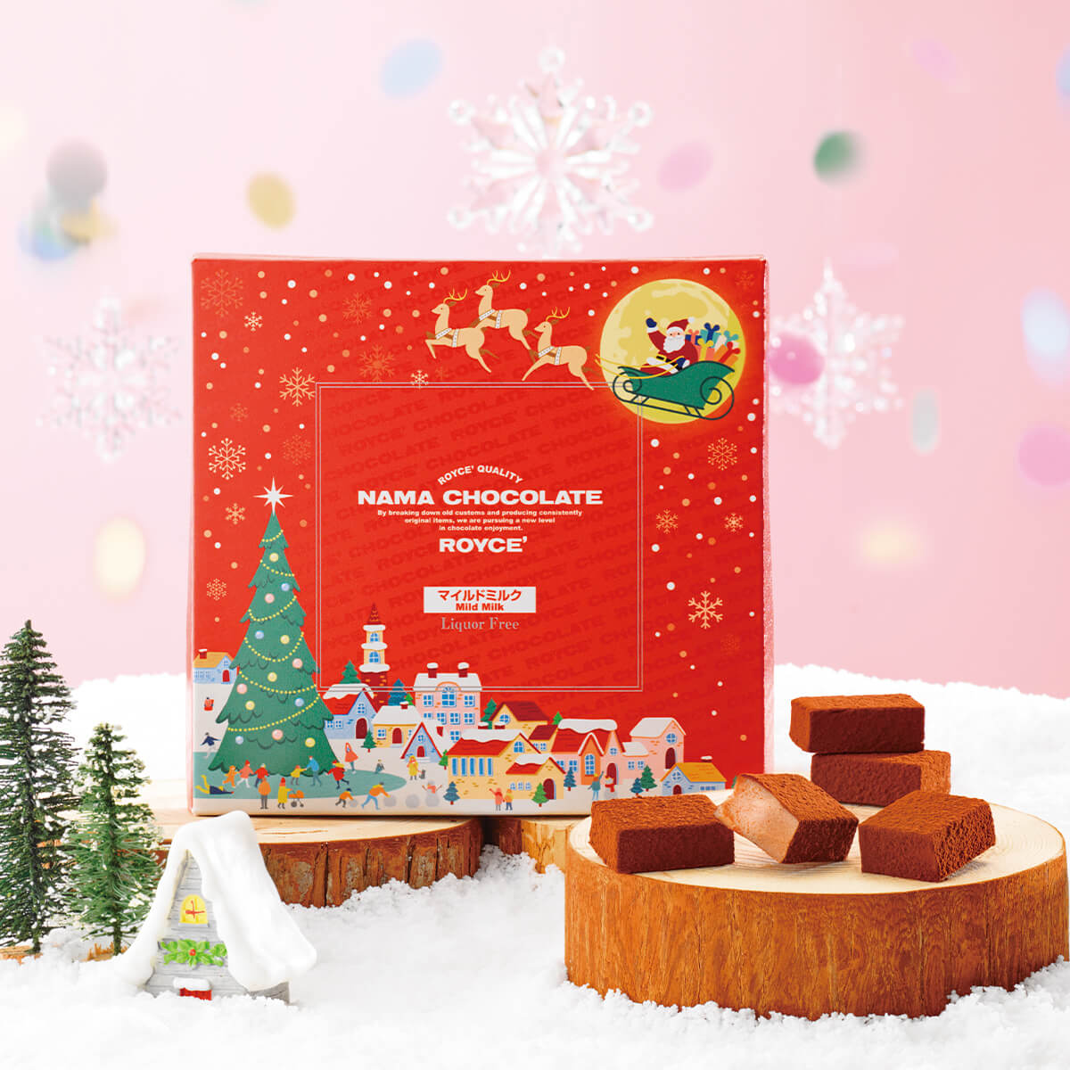 ROYCE' Chocolate - Nama Chocolate "Mild Milk" (Christmas) - Christmas-themed Nama Chocolate box packaging with small chocolate blocks on a wooden stump against a festive background. Accents include little trees and hanging snowflake ornaments.