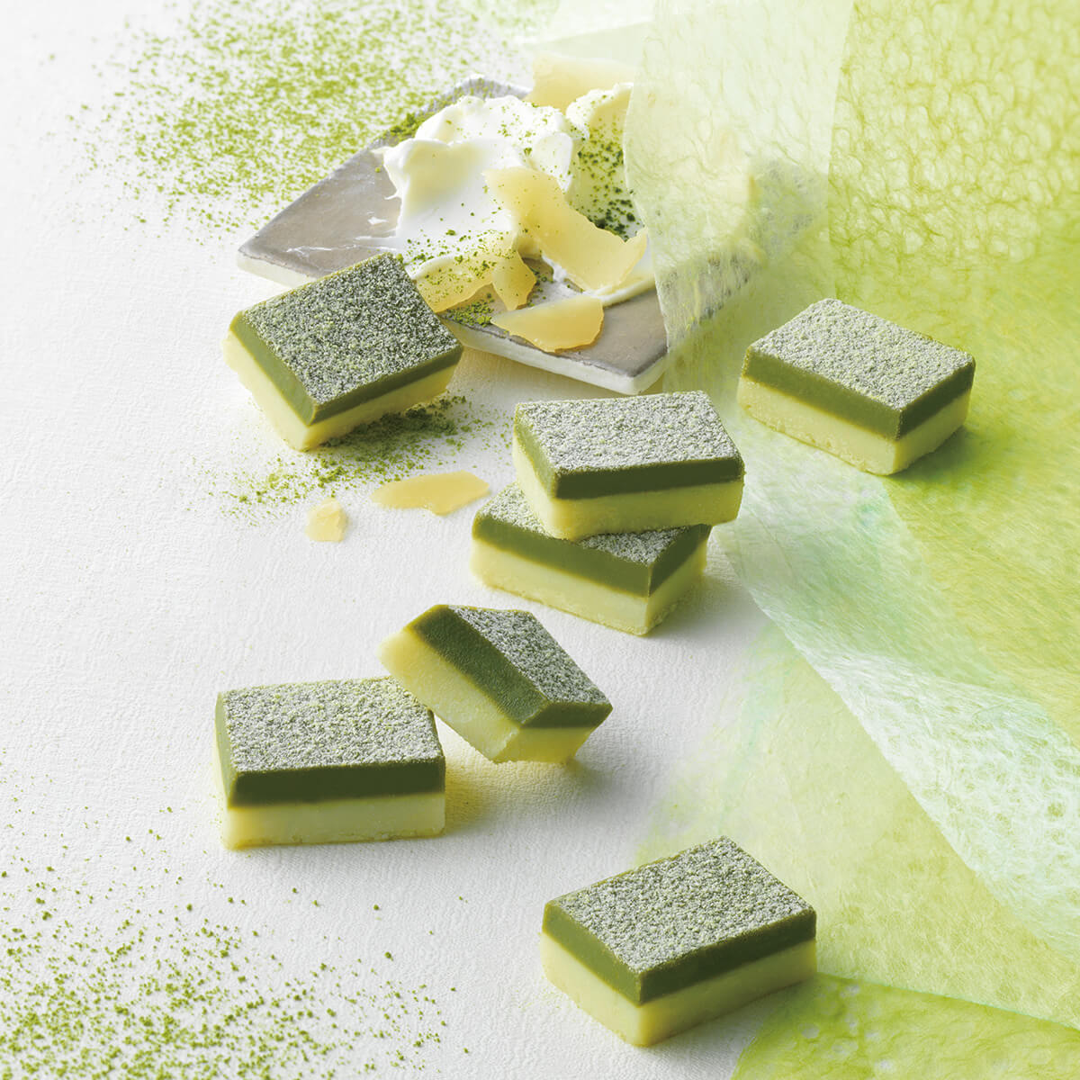 ROYCE' Kyoto Nama Chocolate "Uji Matcha & Fromage" - Image shows two-layered chocolate blocks in green and white on a white and green surface. Accents include a plate with white cream cheese and dustings of matcha powder.