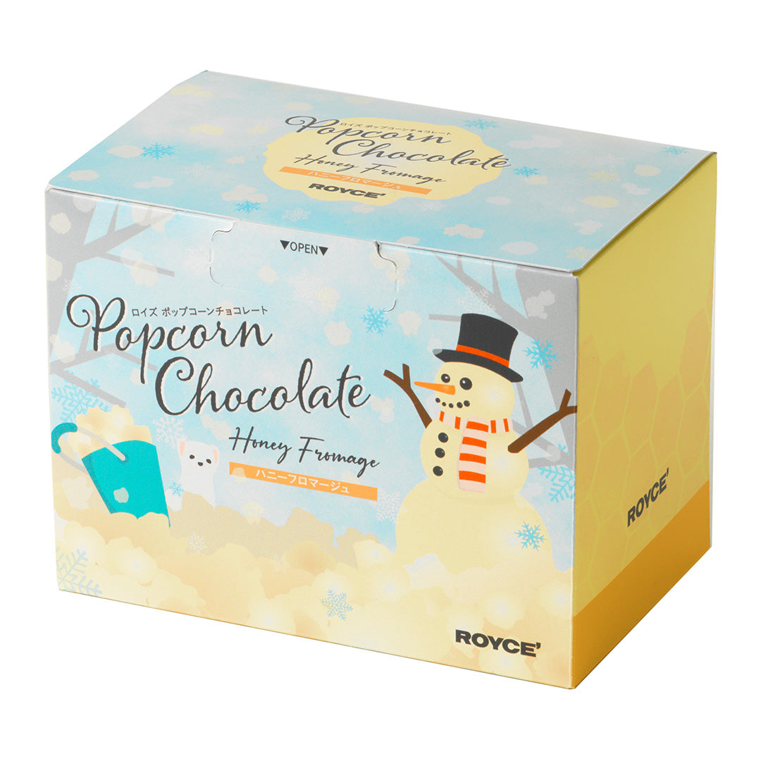 Image shows a printed box with illustrations of a snowman and other drawings. Text says Popcorn Chocolate Honey Fromage ROYCE'. Background is in white.