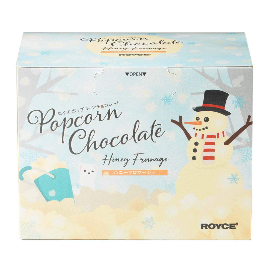 Image shows a printed box with illustrations of a snowman and other drawings. Text says Popcorn Chocolate Honey Fromage ROYCE'. Background is in white.