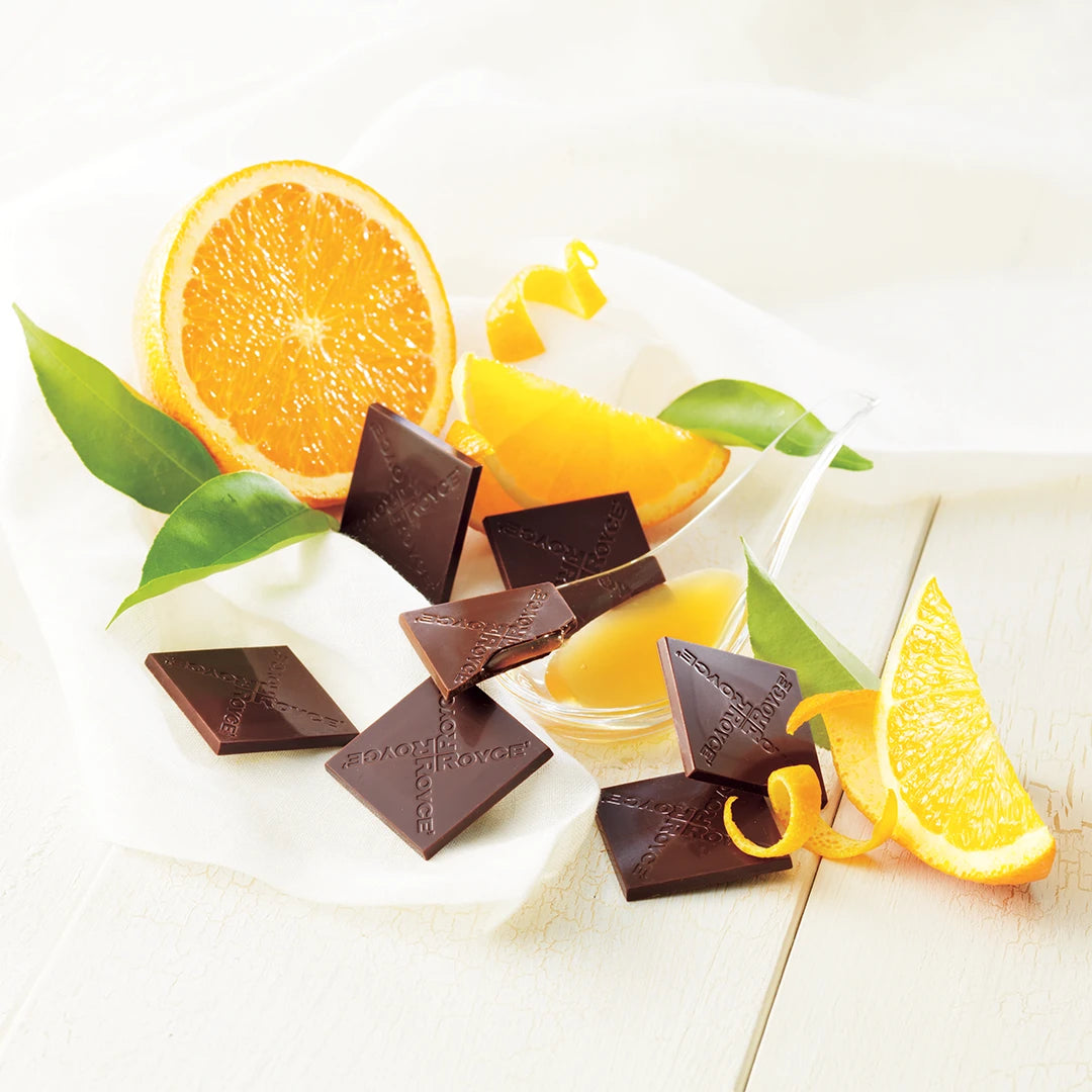 Prafeuille Chocolat Orange features milk chocolate squares with zesty orange sauce, shown with orange wedges, citrus leaves, and chocolate squares branded ROYCE.