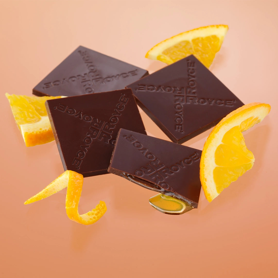 Prafeuille Chocolat Orange: Dark chocolate squares with ROYCE logo, paired with fresh orange slices, showcasing a blend of milk chocolate and zesty orange sauce.