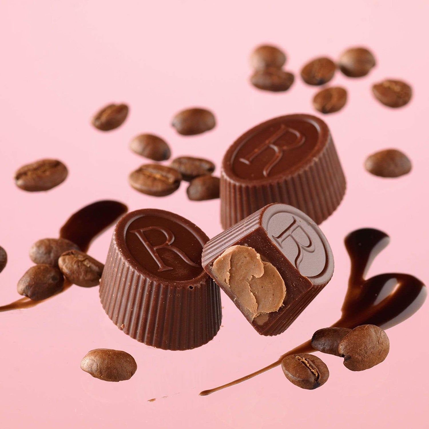 ROYCE' Chocolate - ROYCE' R Chocolat "Caffé Mocha" - Image shows brown oval-shaped chocolates with brown coffee beans and a drizzles of chocolate syrup. Background is in pink.
