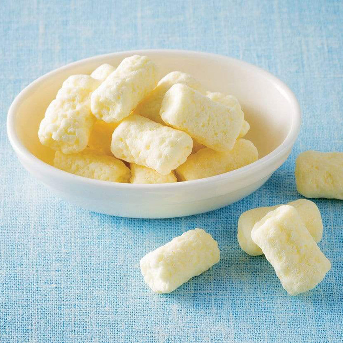 ROYCE' Chocolate - Marshmallow Chocolate "White" - Image shows white chocolate-coated marshmallows in a white bowl. Background is a blue cloth surface with accents of more white chocolate-coated marshmallows.