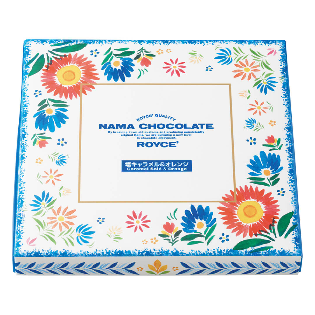 ROYCE' Chocolate - Nama Chocolate "Caramel Salé & Orange" - Image shows a white box painted with blue leaves and flowers in blue, red, and pink with green leaves. Blue text inside gold box says ROYCE' Quality Nama Chocolate By Breaking Down Old Customs And Producing Consistently Original Items, We Are Pursuing A New Level In Chocolate Enjoyment. ROYCE' Caramel Salé & Orange.