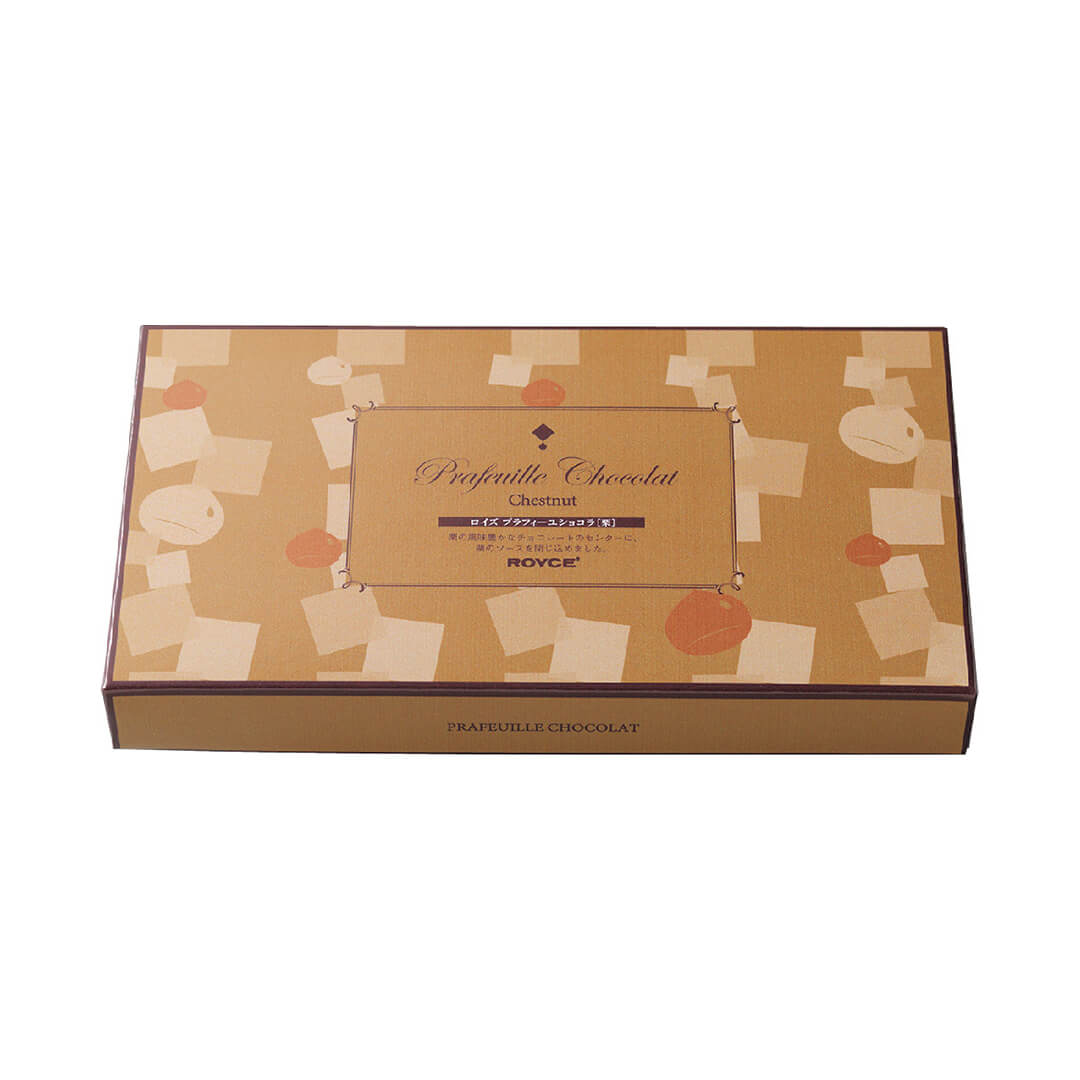 Image shows a brown box with prints of squares and circles. Text in the middle says Prafeuille Chocolat Chestnut. ROYCE'. Text on bottom part says Prafeuille Chocolat.