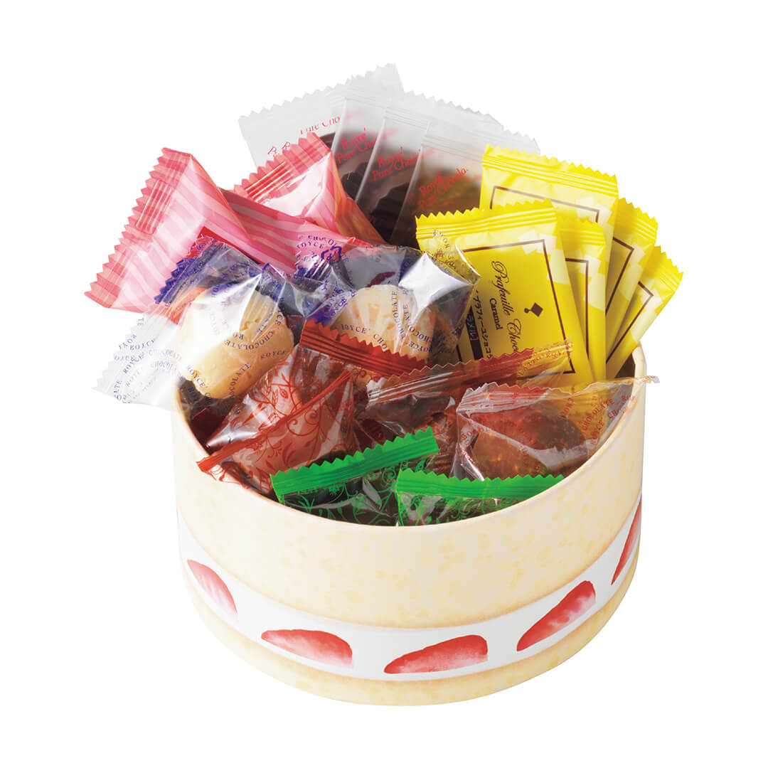 Image shows a yellow round box with white trim and illustrations of red strawberries. Inside the box are a variety of individually-wrapped confections in the colors white, pink, red, green, and yellow in different shapes and sizes. Background is in white.