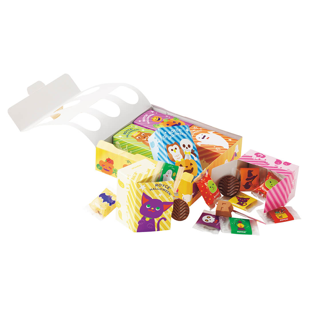 Image shows an open yellow printed box together with small boxes in the colors of green, violet, blue, orange, yellow, and pink. Seen in the picture are illustrations of ghosts, ghouls, animals, and other Halloween characters. Texts seen in the picture say ROYCE' Halloween. ROYCE'. Accents include loose wrapped chocolates in yellow, red, orange, and violet together with brown chocolate discs and an R-shaped chocolate. Background is in white.