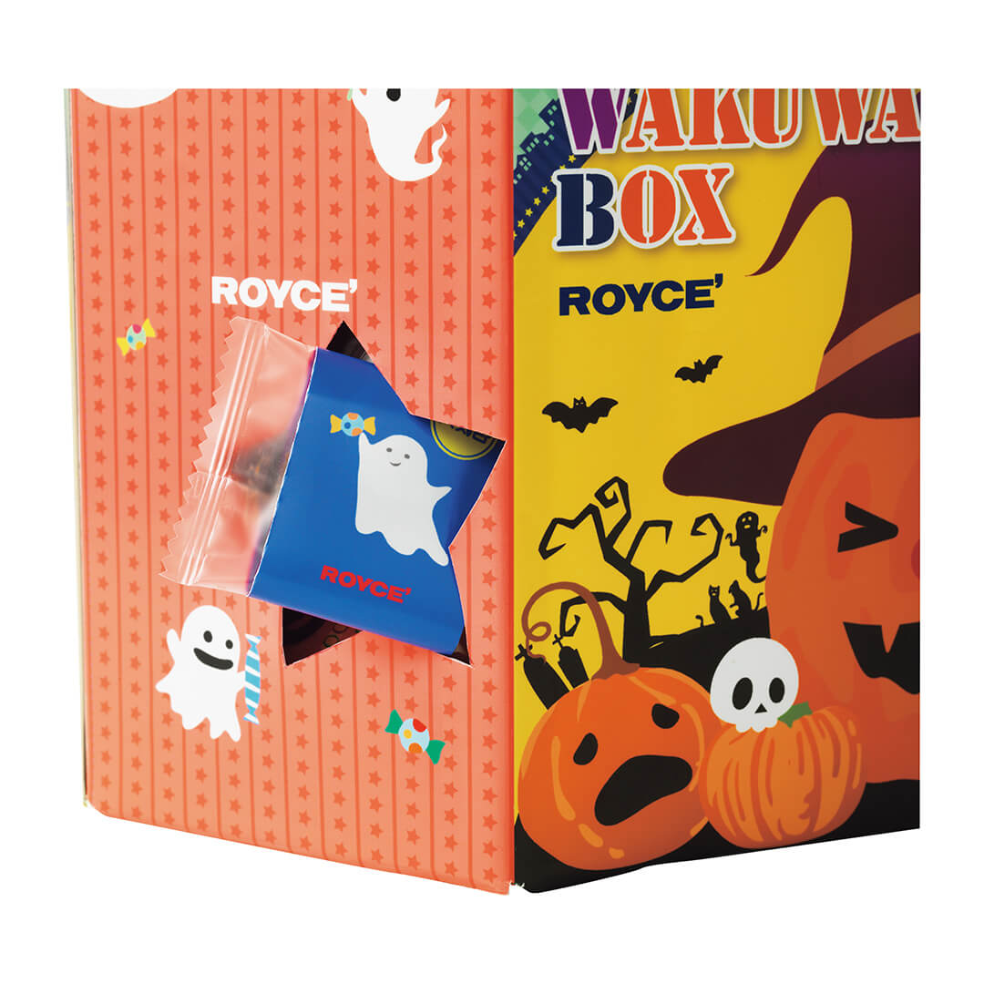 Image shows a printed box portion in the colors of red, yellow, orange, blue, and black. Seen are illustrations of stars, candies, ghosts, pumpkins, skulls, trees, bats, tombstones, and cats. Also seen on the side is a star-shaped cutout with a wrapped chocolate peeking out in color blue with a ghost print. Also on the box are the word ROYCE' in white, red, and blue. There are also the words Wakuwaku Box on the upper right. Background is in white.