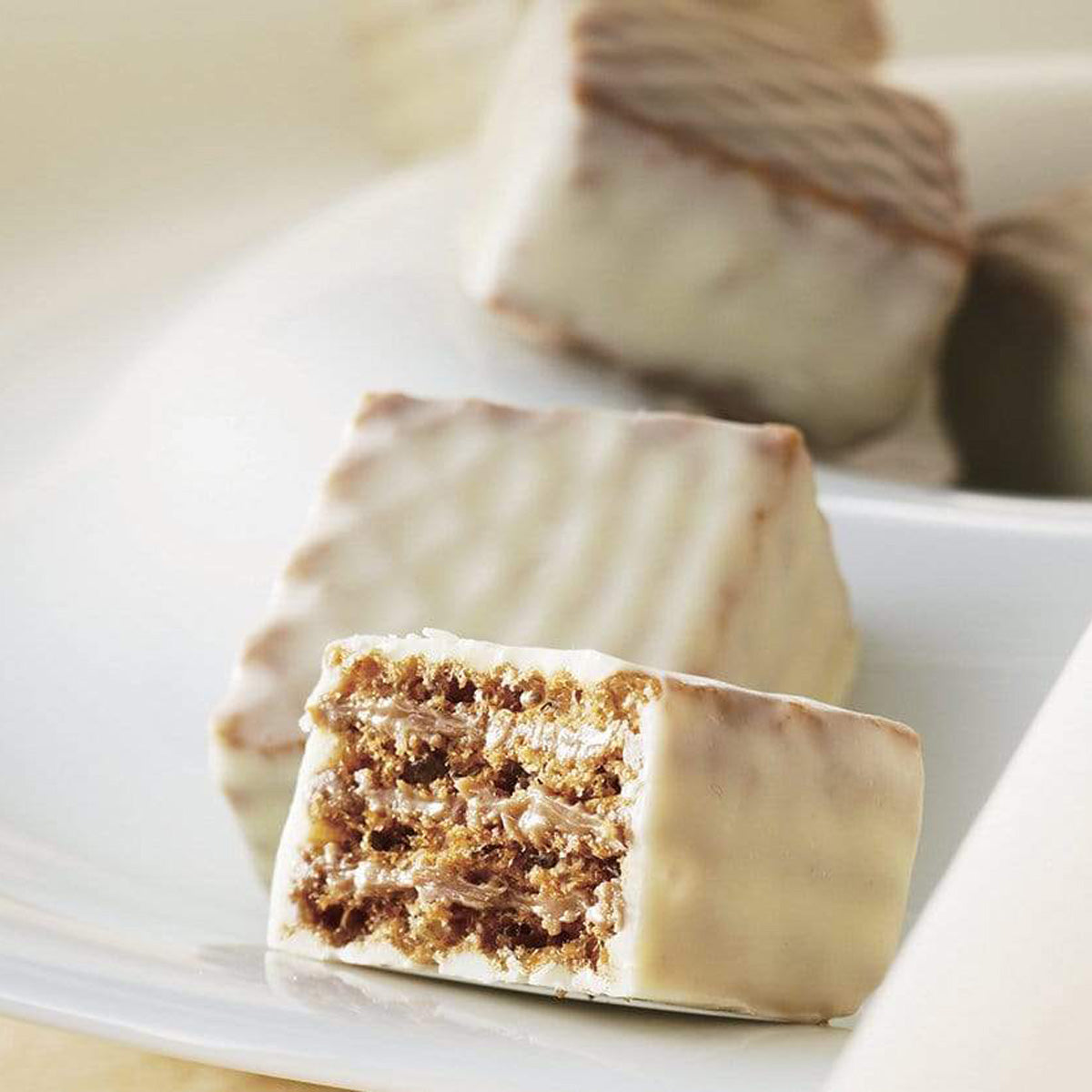 ROYCE' Chocolate - Chocolate Wafers "Tiramisu Cream" - Image shows white chocolate wafers on a white plate. Background is white with blurry white chocolate wafers.