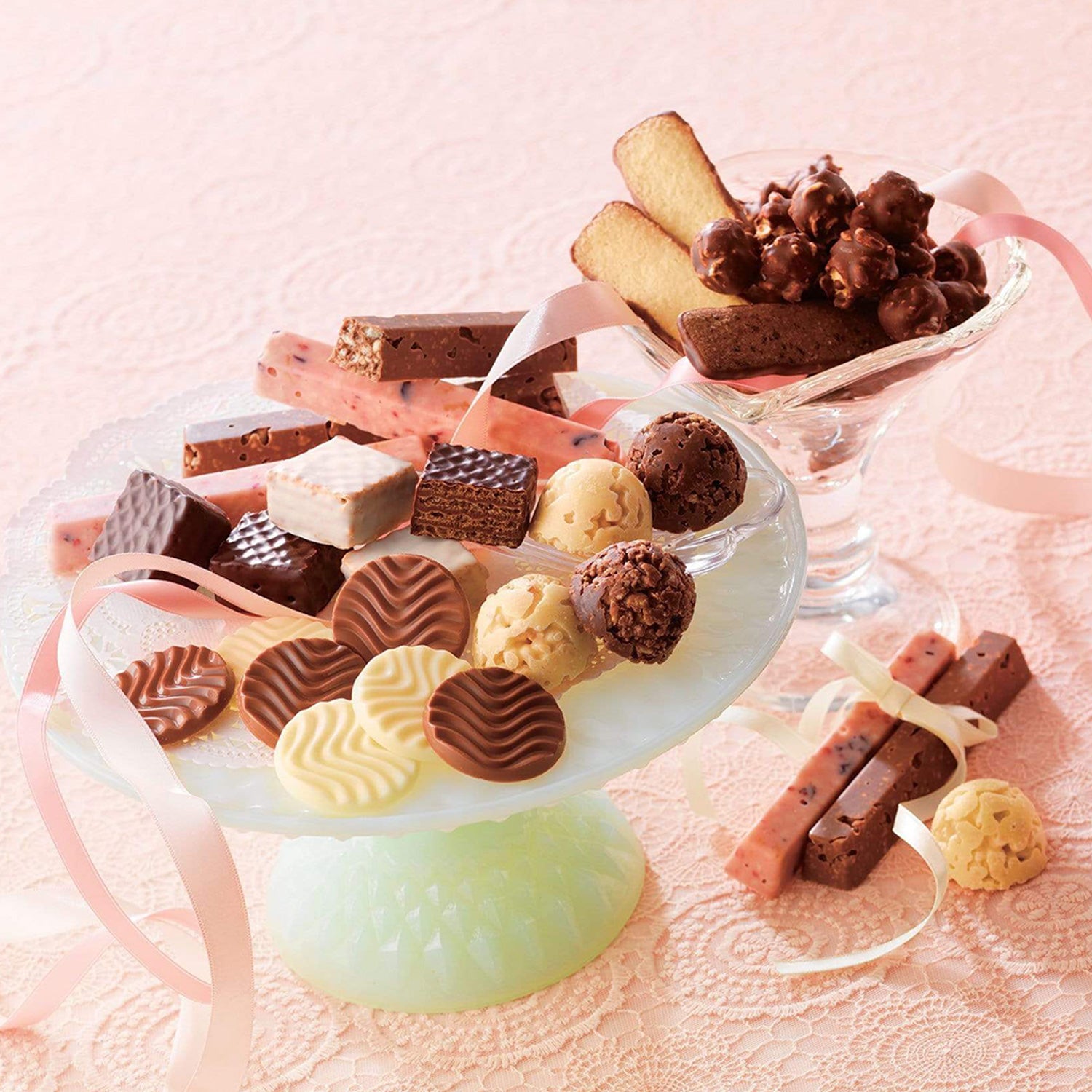 ROYCE' Chocolate - Chocolate Selection "ROYCE' Sweet Season" - Image shows a serving plate and glass filled with different confections in varying shapes, sizes, and colors of brown, white, and yellow. Accents include pink and white ribbons and a pink tablecloth.