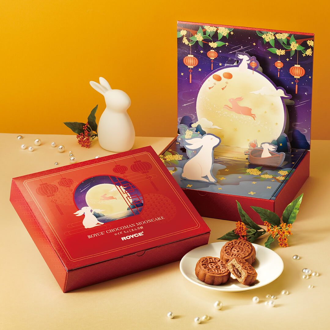 ROYCE' Chocolate - Chocoman Mooncake - Image shows two printed boxes with rabbit and moon illustrations. Accents include pearls, a rabbit figuring, and a plate with mooncakes.