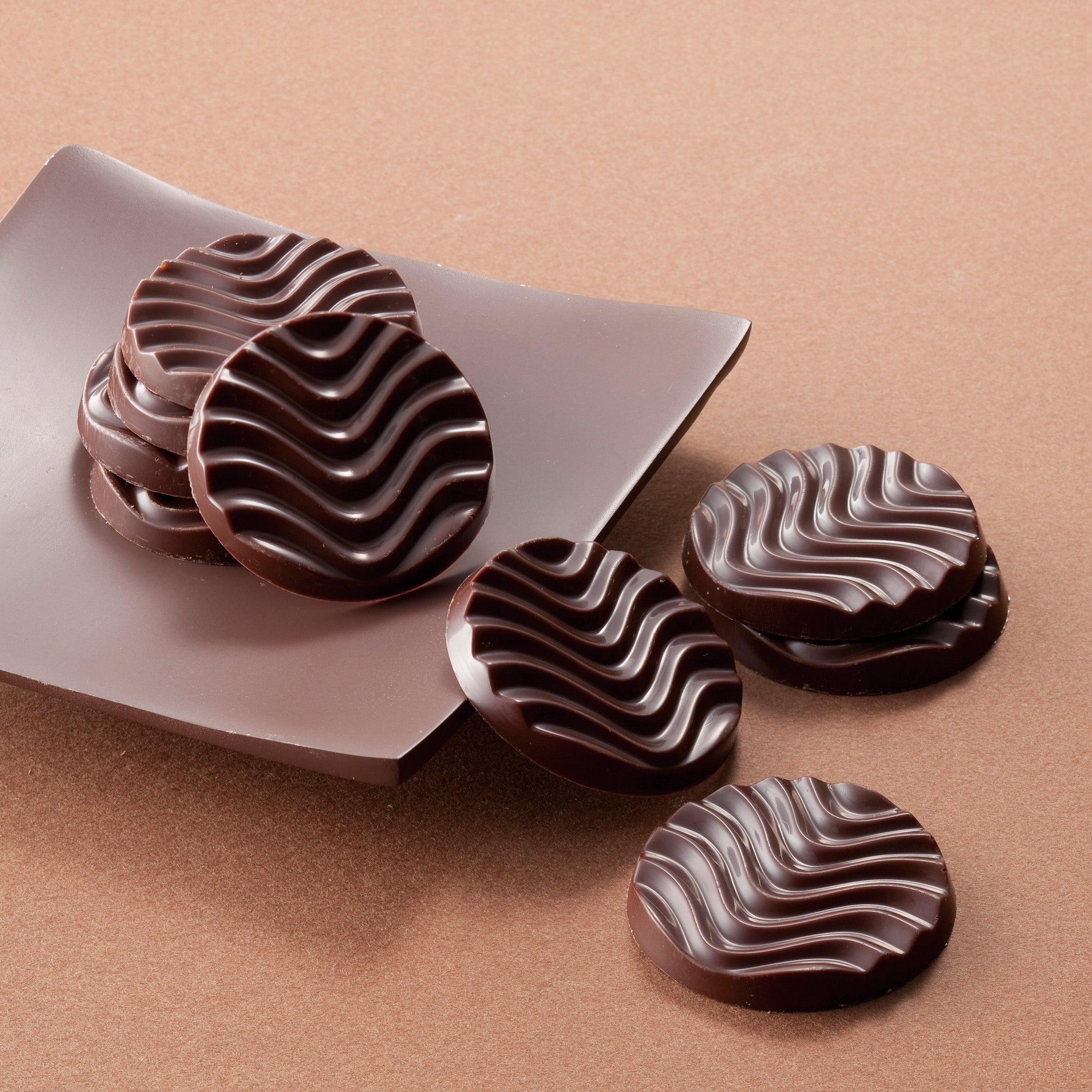 Image shows brown chocolate discs on a brown plate.