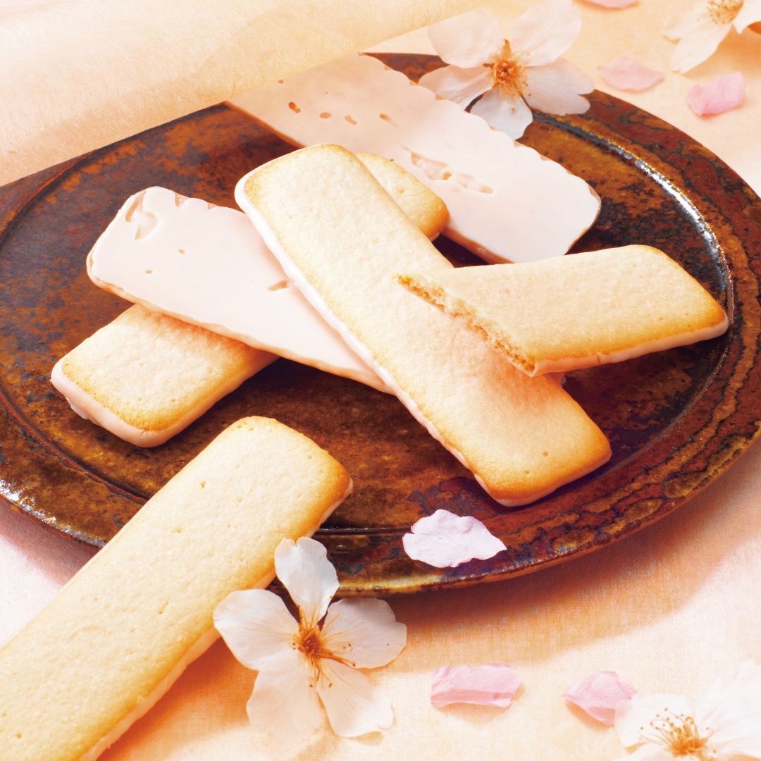 Image shows cookies on a brown plate with flowers for accents.