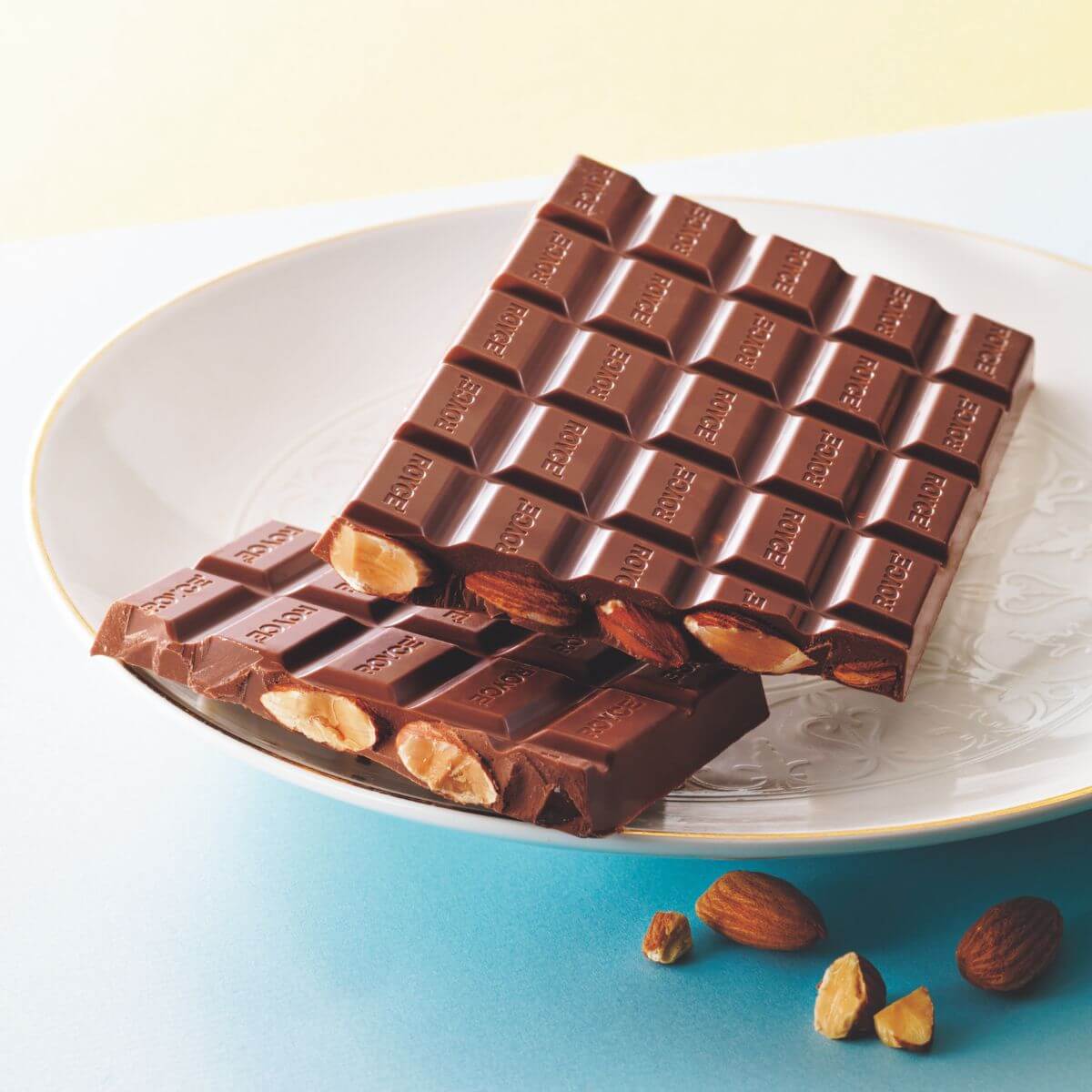 Chocolate Bar "Almond" has a milk chocolate bar filled with almonds. Image shows a chocolate bar filled with almonds on a white plate.