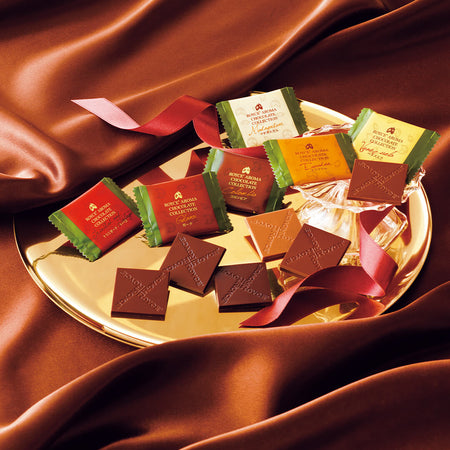 ROYCE' Chocolate - ROYCE' Aroma Chocolate Collection -  Image shows a individually-wrapped chocolate squares on a gold plate. Accents include red silk and a red ribbon. 