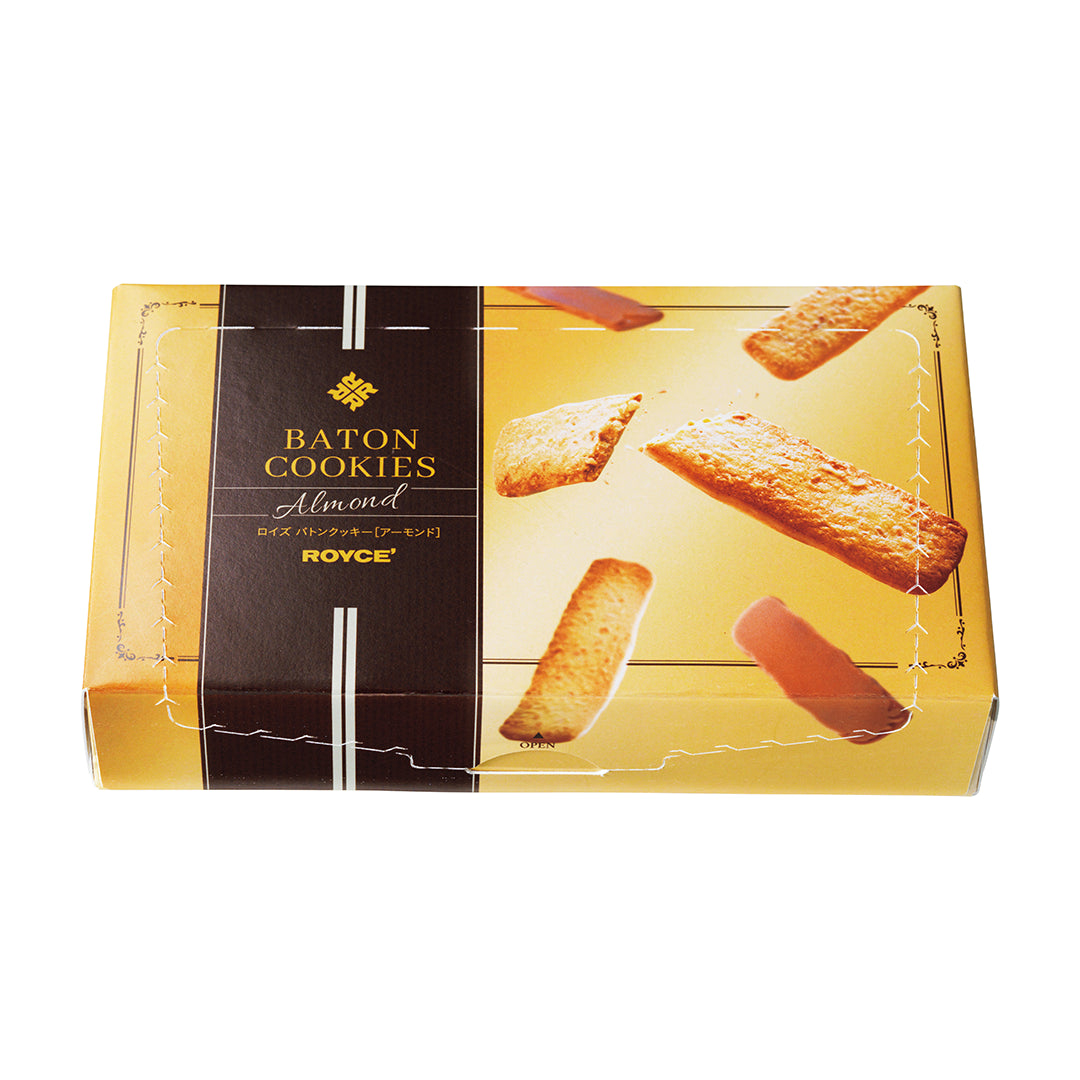 Baton Cookies "Almond" -  A rectangular box of ROYCE' Baton Cookies, Almond flavor, shown on a plain white background. The packaging is gold with a dark brown vertical detail on the left with text saying Baton Cookies Almond ROYCE'.
