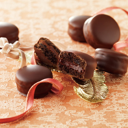 Cacao Macaron (6 Pcs) - Image shows chocolate-coated macarons with accents of a ribbon and golden leaf.