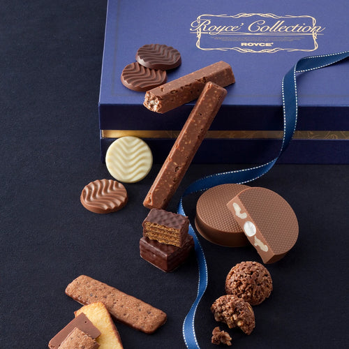 ROYCE’ Collection Blue gift box featuring assorted premium chocolates and biscuits, including wave-patterned discs, biscuit sticks, wafers, and chocolate-dipped cookies, elegantly tied with a blue ribbon.