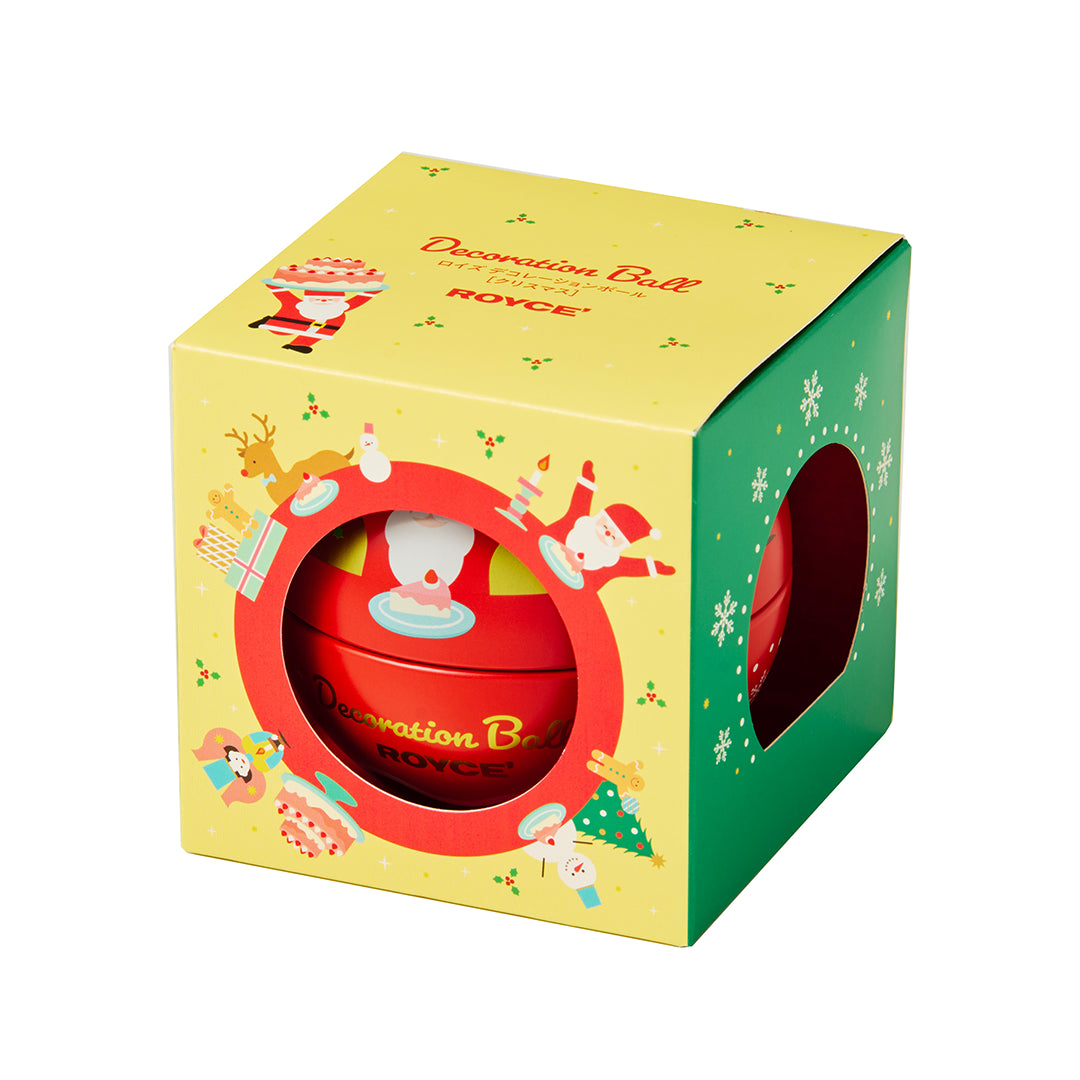 A red spherical decorative ornament by ROYCE, presented inside a festive yellow and green gift box with Christmas illustrations and a circular cutout showing the ornament.