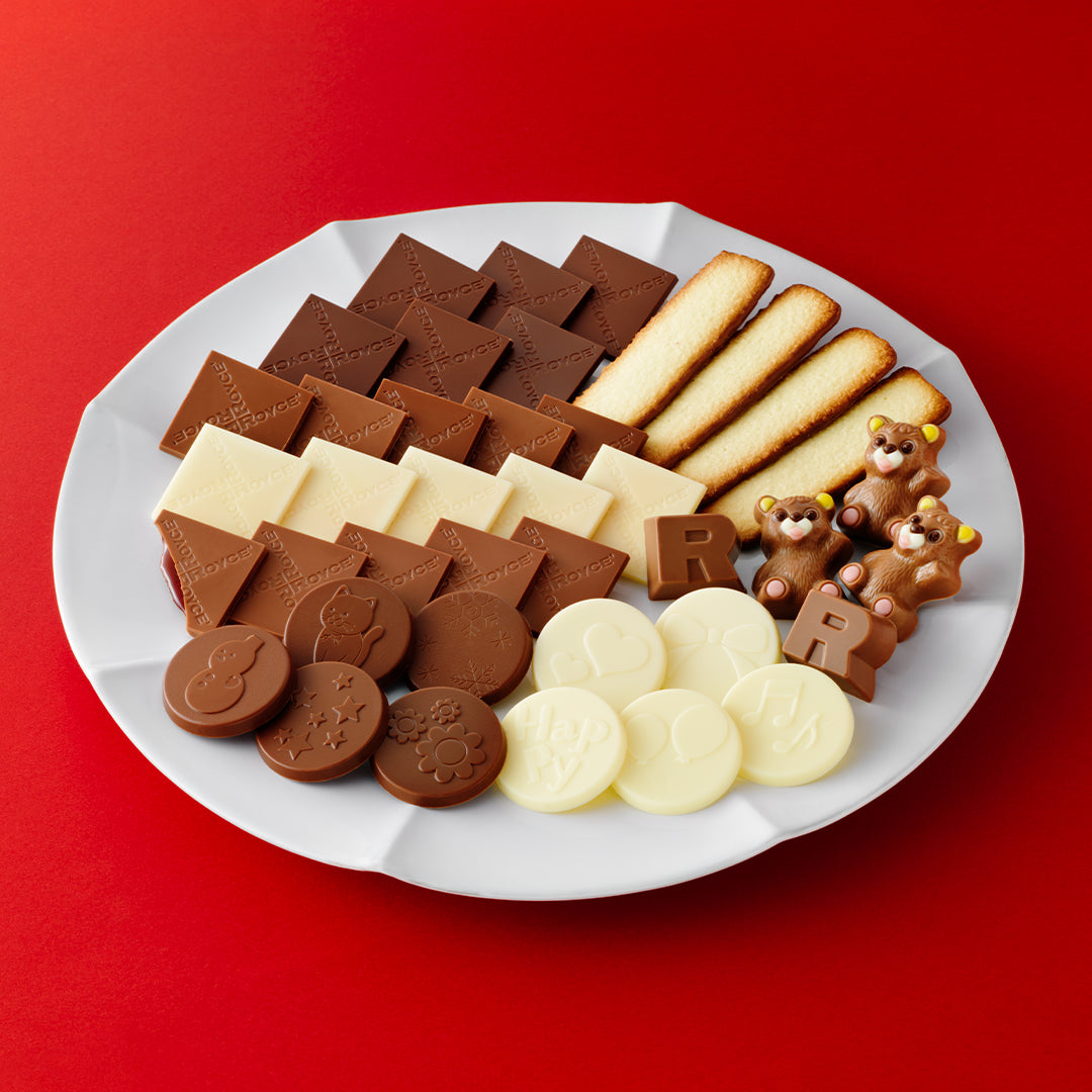 Image shows chocolates and cookies on a white plate. Background is in red.