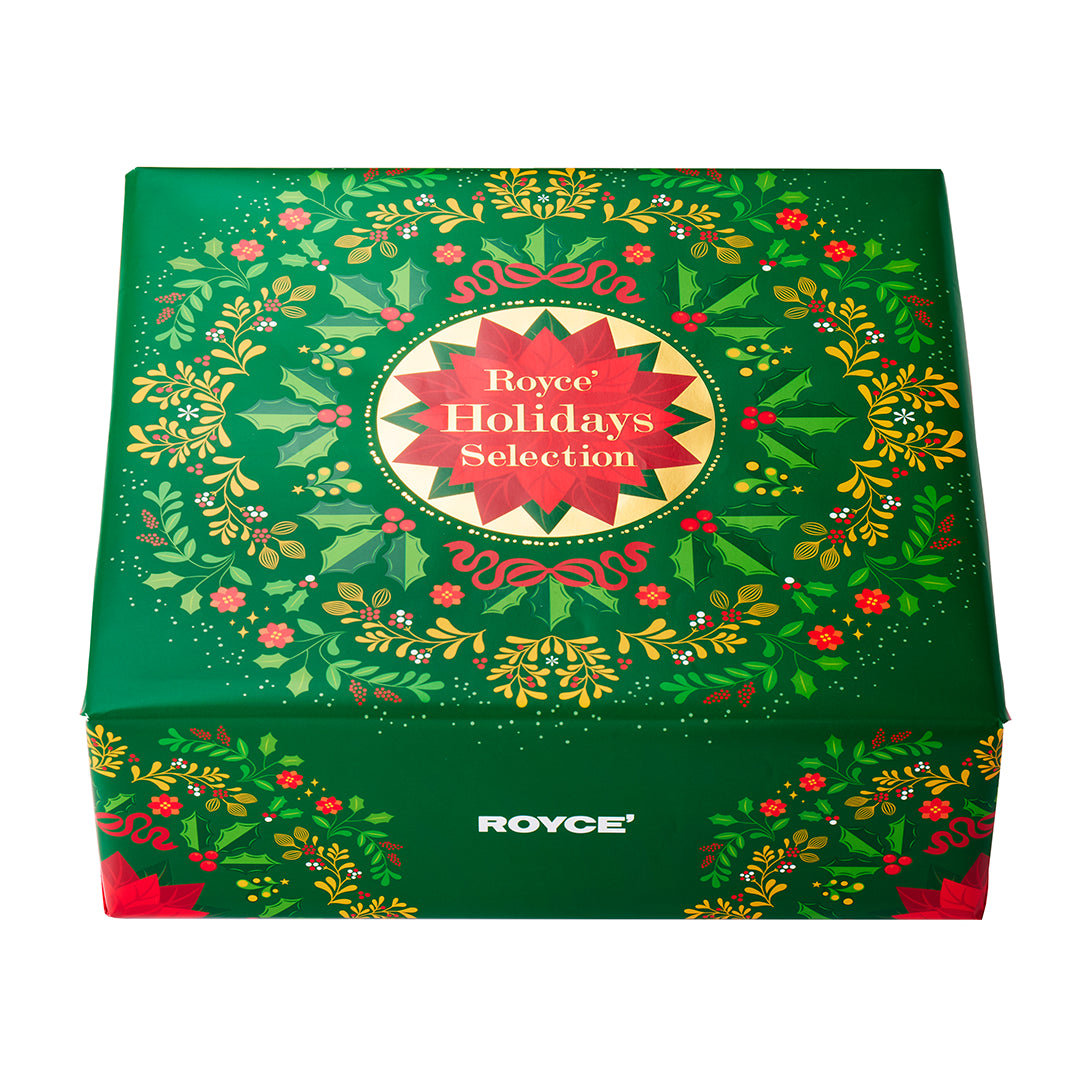 A square green gift box with a festive holiday wreath design and a central red and gold label reading 'Royce Holidays Selection.' The brand name ROYCE is also printed near the bottom front.