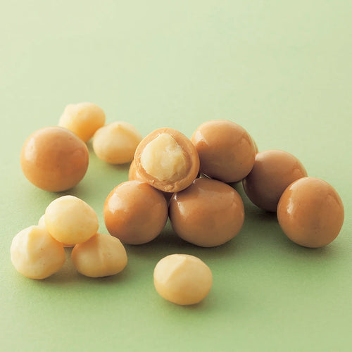 Macadamia Gianduja Chocolate: A mix of plain and glossy candy-coated macadamia nuts, showcasing a cut nut revealing its creamy kernel inside.
