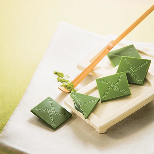 Prafeuille Chocolat Matcha on a ceramic tray, featuring diamond-shaped green-tea chocolates with ROYCE logo, and a bamboo spoon with matcha powder in the background.