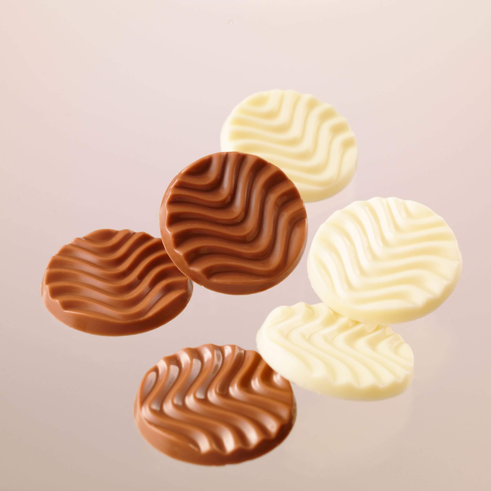 ROYCE' Chocolate - Pure Chocolate "Creamy Milk & White" - Image shows brown and white chocolate discs with a waved texture. Background is light brown in color.