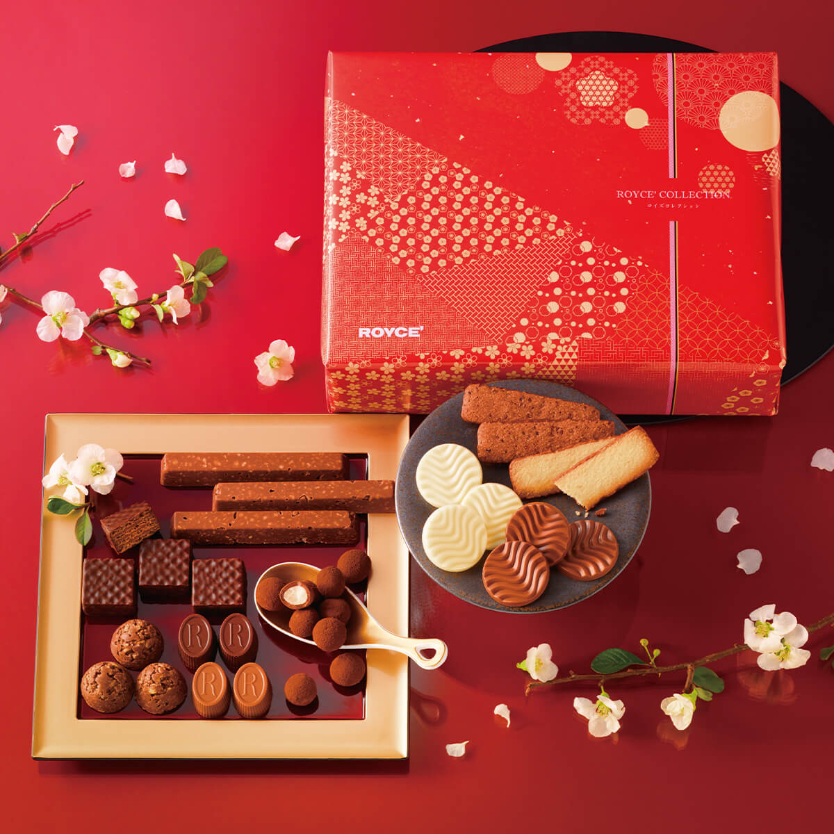 ROYCE' Chocolate - Image shows a red printed box on the right with text saying ROYCE' Collection ROYCE'. Lower left side shows chocolates of different shapes in square- and circle- shaped plates. Accents include flowers. Background is in red.