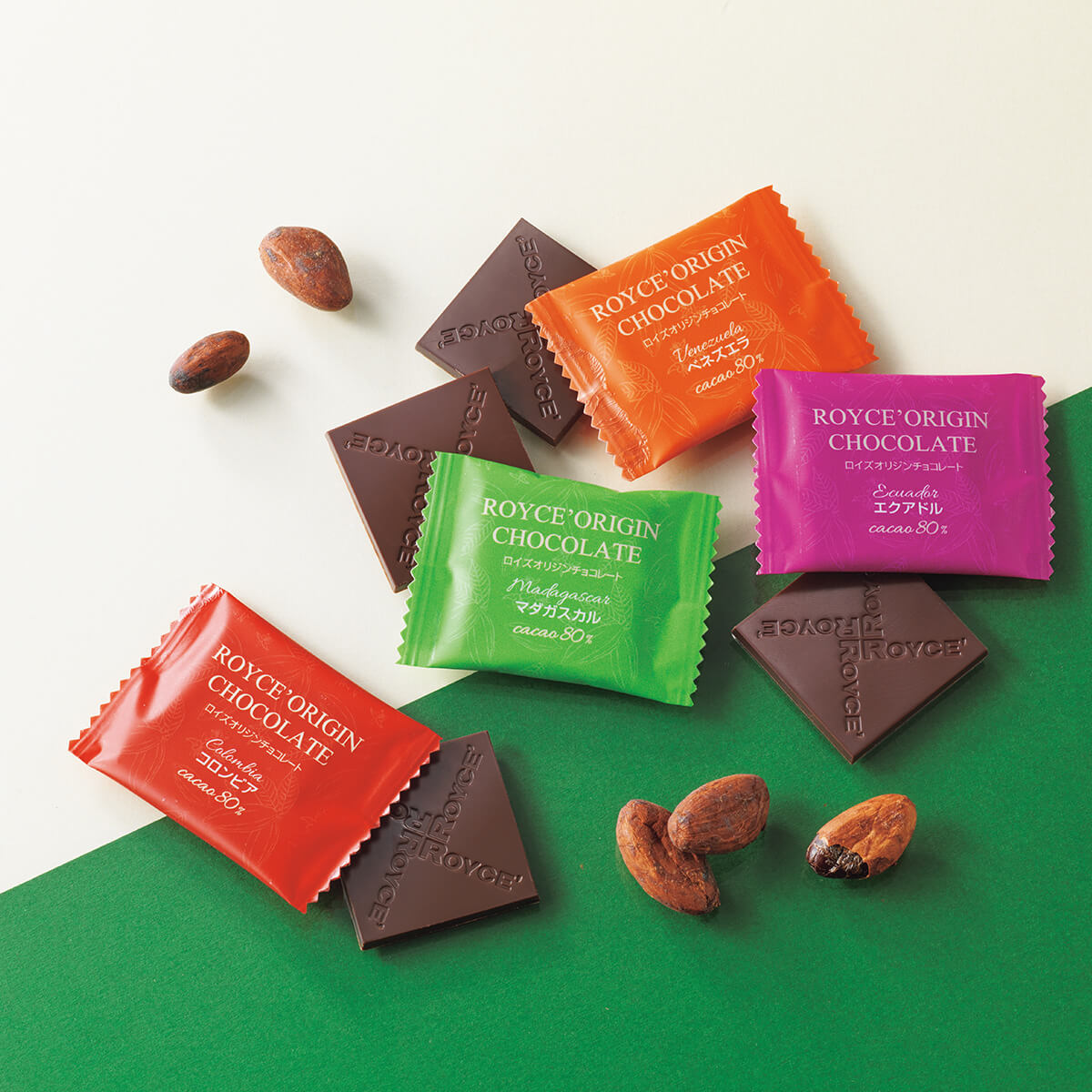 ROYCE' Chocolate - Image shows brown chocolate squares with the word ROYCE' etched on them and wrapped chocolates in red, orange, green, and pink with text saying ROYCE' Origin Chocolate. Accents include loose cacao beans.