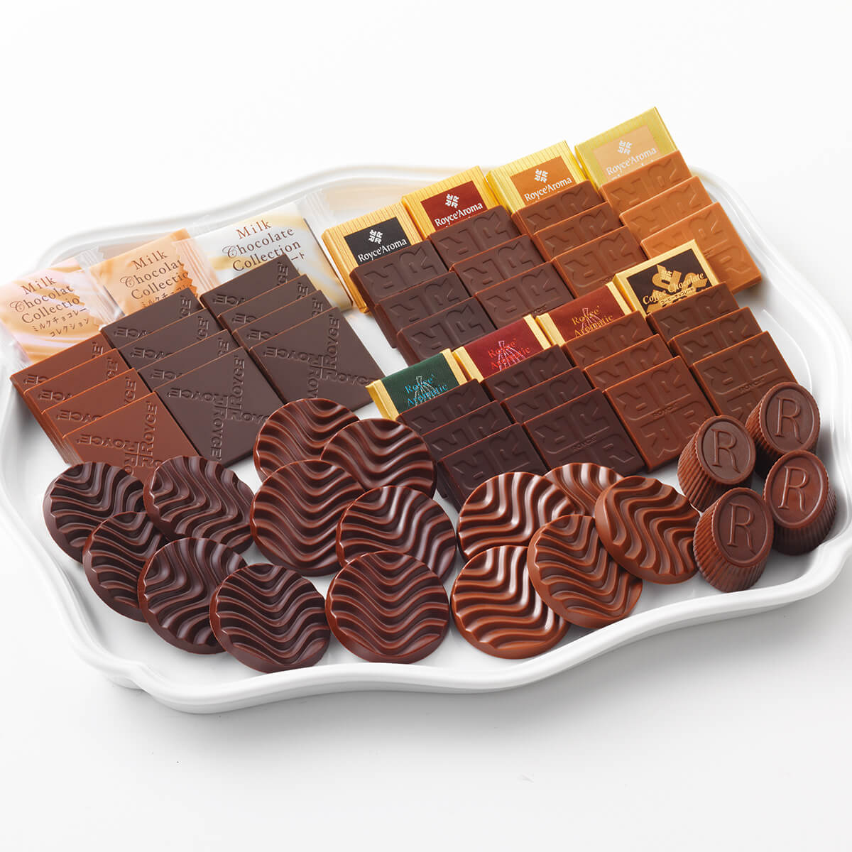ROYCE' Chocolate - ROYCE' Tasting Box - Image shows different kinds of chocolates in various shapes, sizes, and colors. They are arranged on a white tray with curved details.