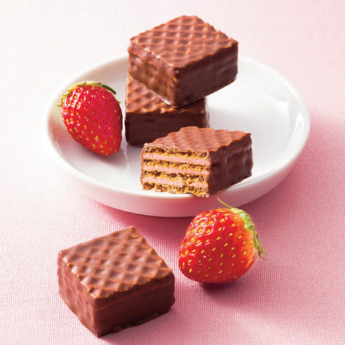Chocolate Wafers Strawberry Cream (12 Pcs) on a plate, showcasing crispy layers and pink filling, accompanied by fresh strawberries, against a soft backdrop.