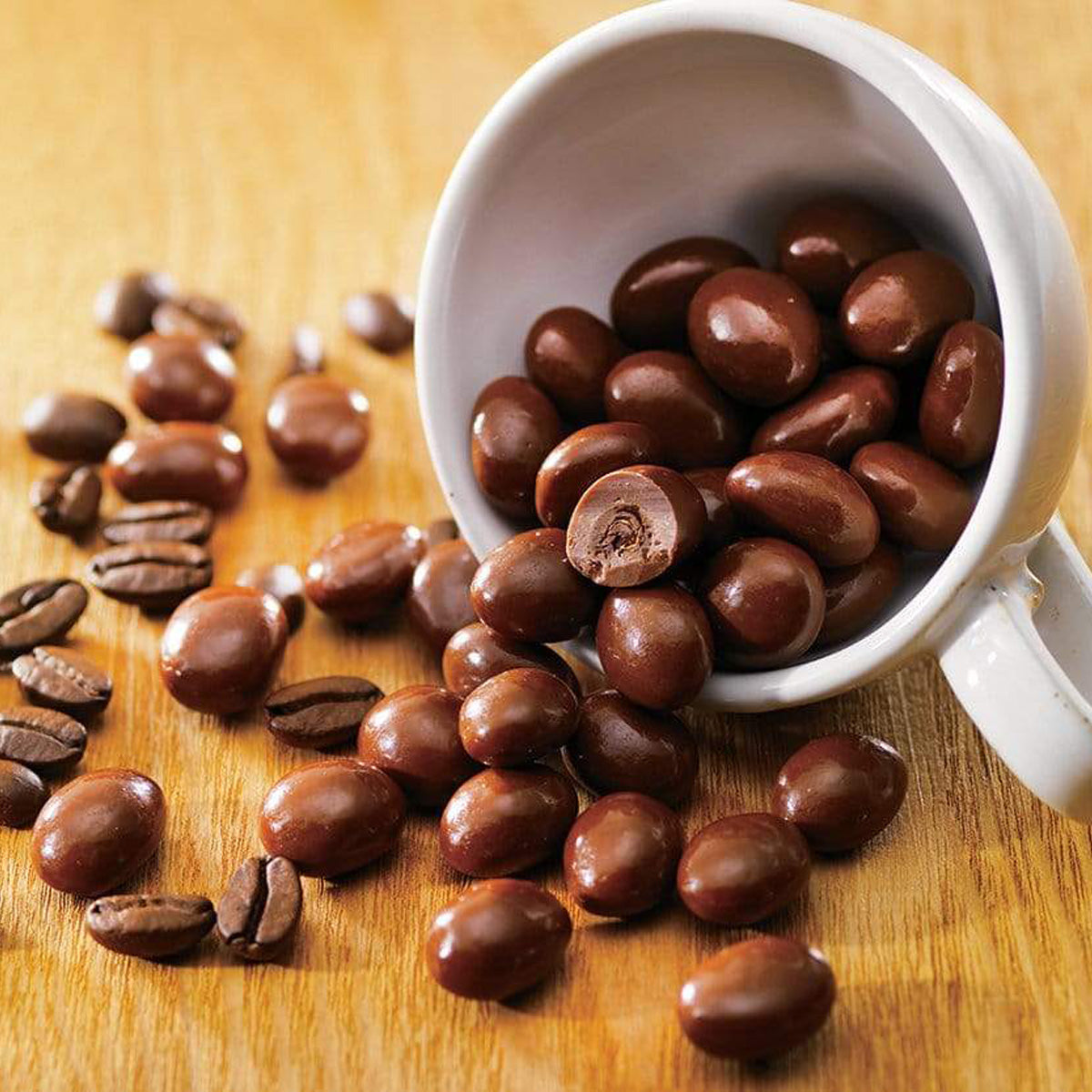 ROYCE' Chocolate - Coffee Beans Chocolate - Image shows brown chocolate-coated coffee beans. Accents include a white cup and a golden wooden background.
