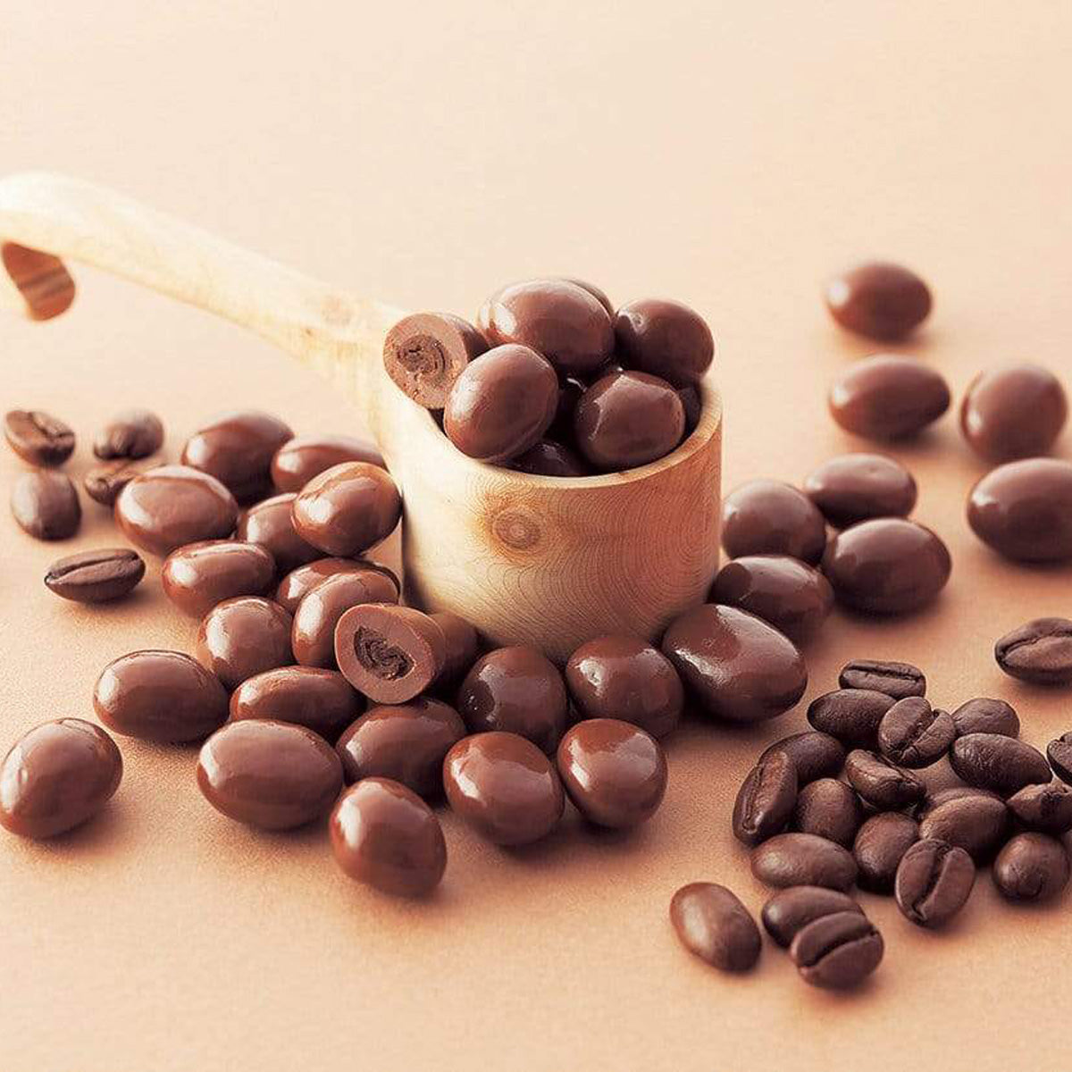 ROYCE' Chocolate - Coffee Beans Chocolate - Image shows brown chocolate-coated coffee beans. Accents include a wooden scoop and a light brown background.