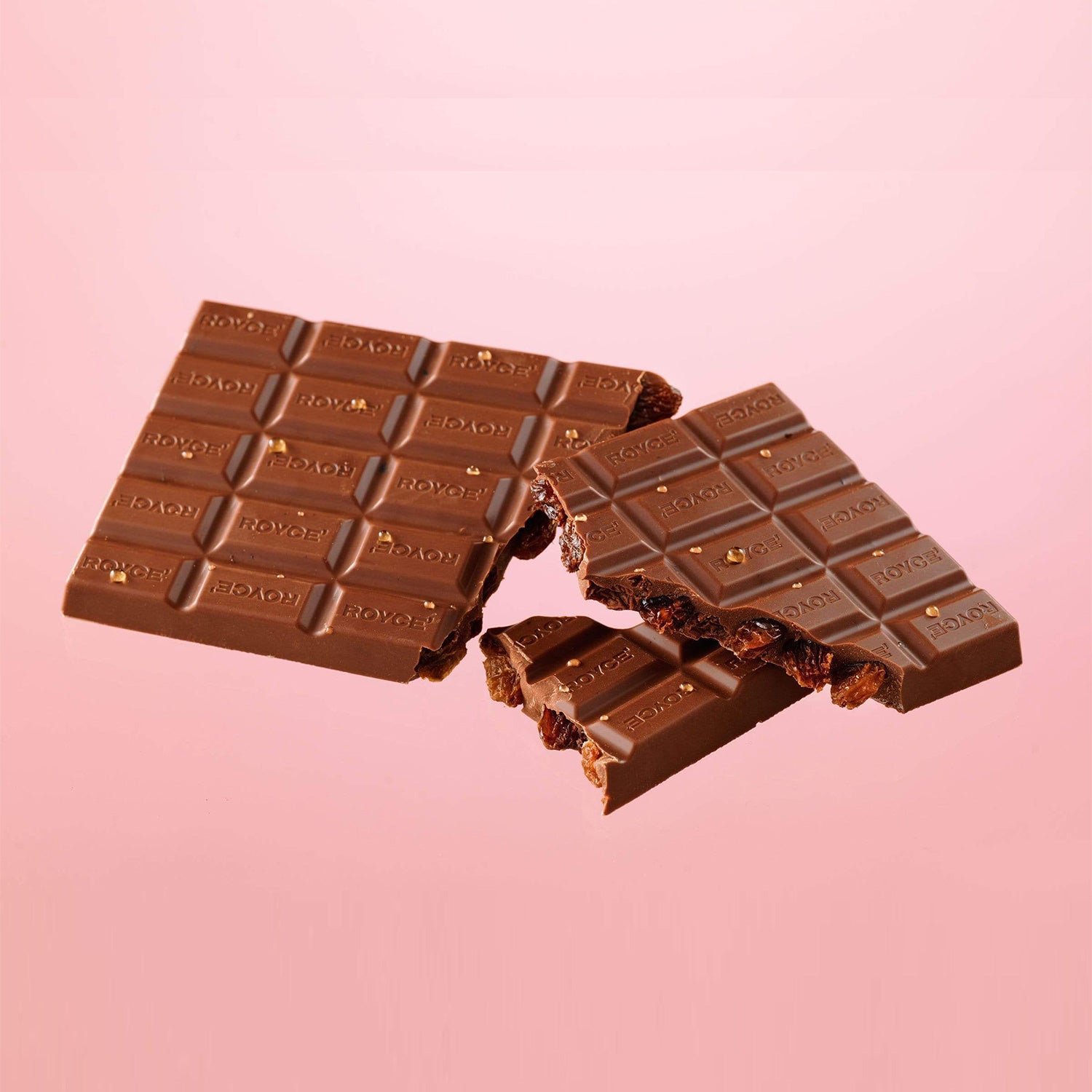 ROYCE' Chocolate - Chocolate Bar "Cognac & Raisin" - Image shows brown chocolate bars with the word ROYCE' engraved multiple times on each. Background is in light pink color.
