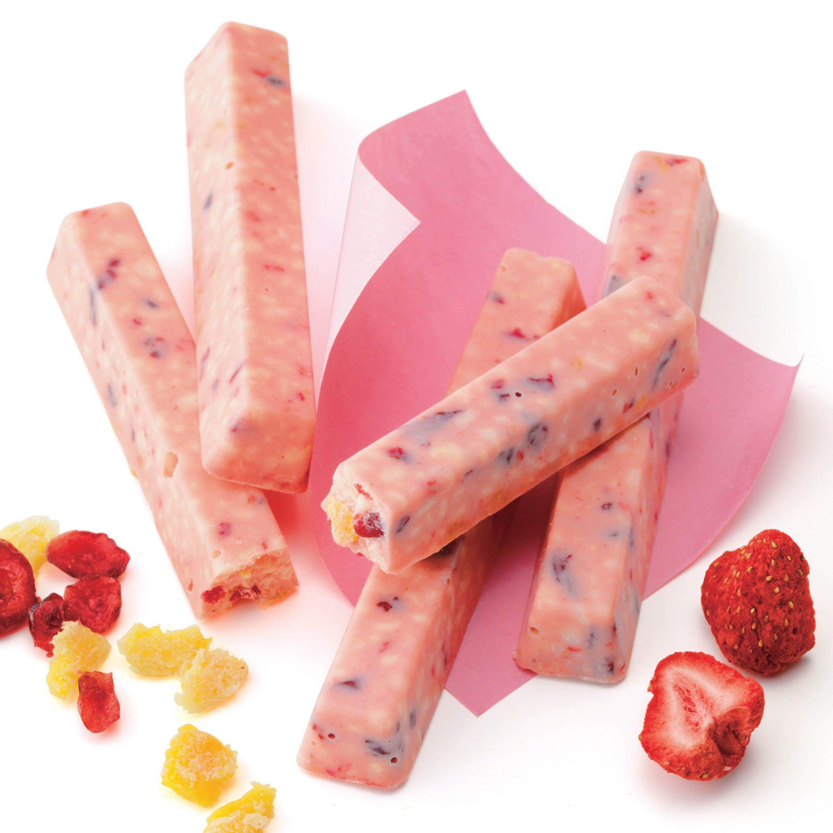 ROYCE' Chocolate - Fruit Bar Chocolate - Image shows pink chocolate bars on a pink plate with fruits such as red berries and yellow fruit chunks. Background is in white and features a pink paper.