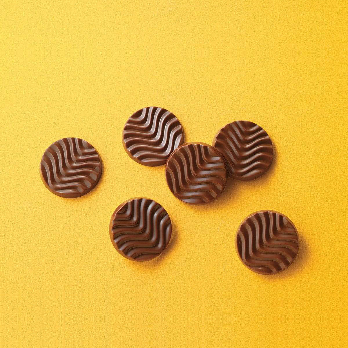 ROYCE' Chocolate - Pure Chocolate "Fruity Milk" - Image shows brown chocolate discs with a waved texture. Background is in color yellow.