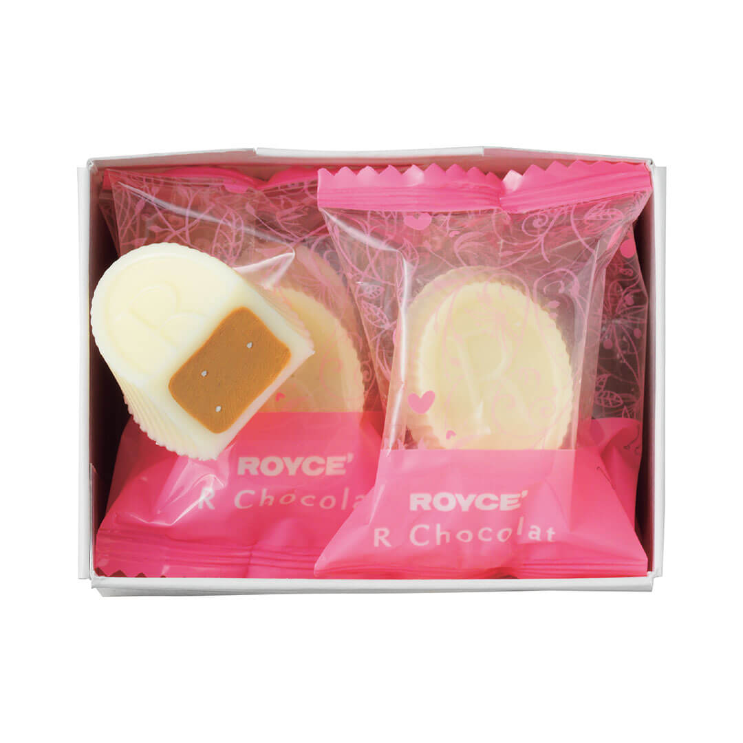 ROYCE' Chocolate - ROYCE' R Chocolat "White Gianduja" - Image shows white oval-shaped chocolates with brown cream. Some chocolates are also wrapped in a chocolate wrapper with pink colors and illustrations with text saying ROYCE' R Chocolat. Background is in white.