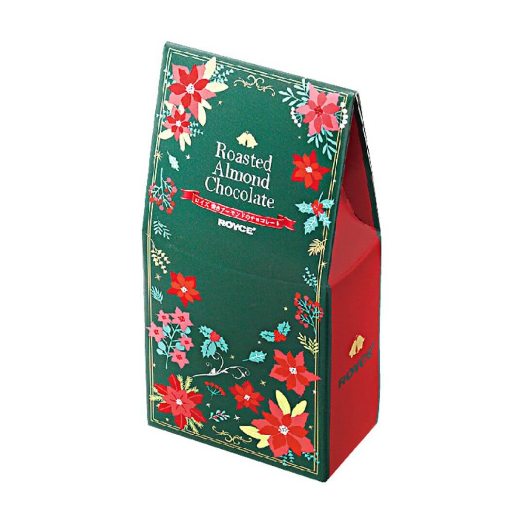 Festive Royce Roasted Almond Chocolate package with poinsettia motifs, containing chocolate-coated roasted almonds, inspired by German Christmas market treats. Exclusively in select US boutiques.