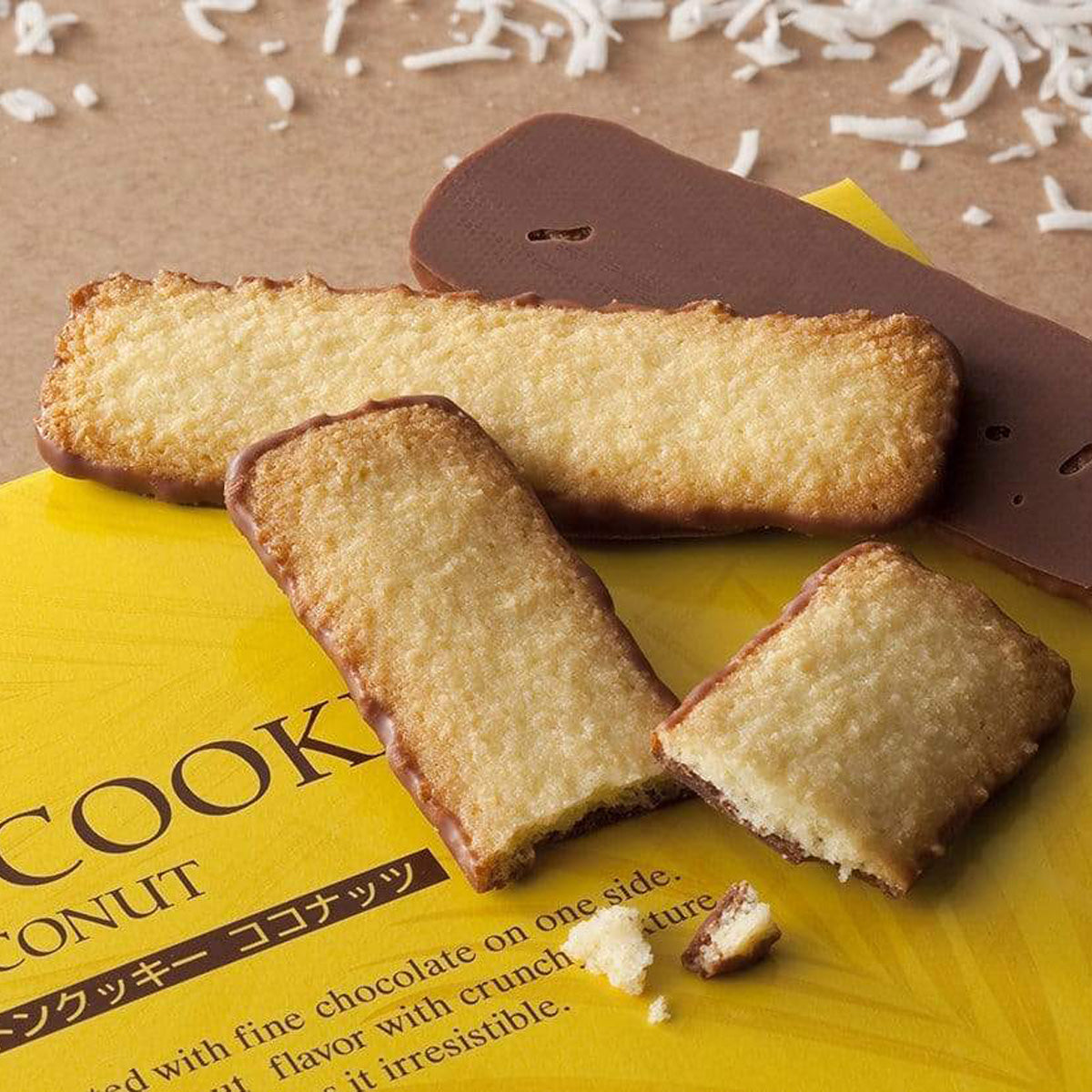 ROYCE' Chocolate - Baton Cookies "Coconut" - Image shows golden cookies with brown chocolate coating on a yellow box with letters and white coconut shavings in the background. 