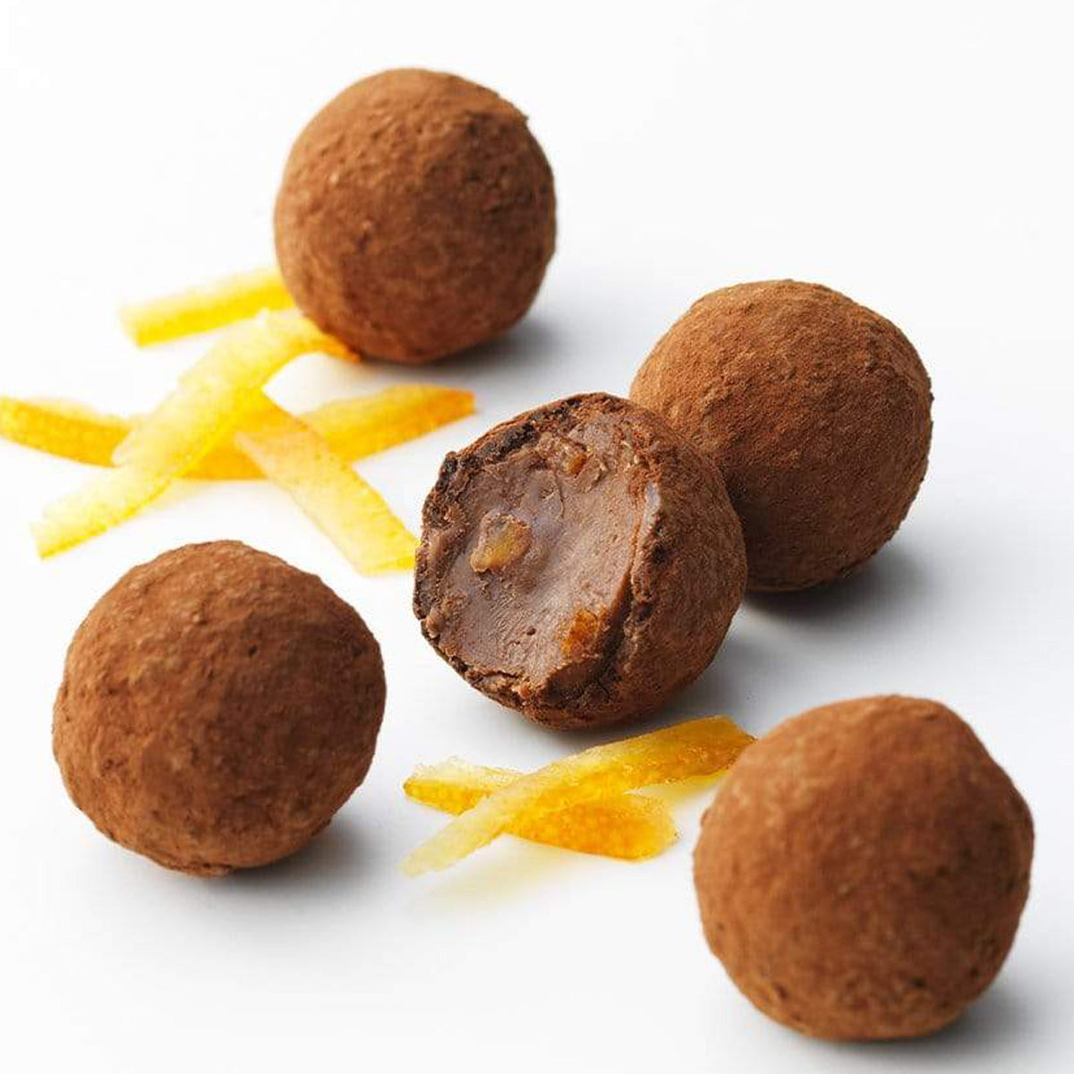 ROYCE' Chocolate - Petite Truffe "Orange" - Image shows brown chocolate balls on a white surface with orange peels.